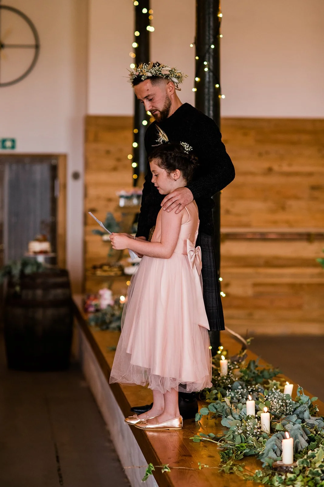 The groom stands beside a young flower girl during the wedding reception.