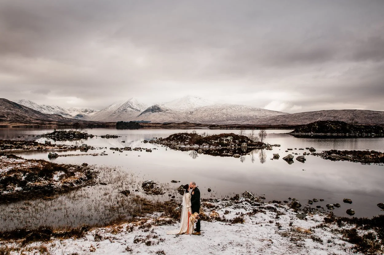 Bride-and-groom-kissing-amongst-a-dramatic-snowy-Glencoe-backdrop