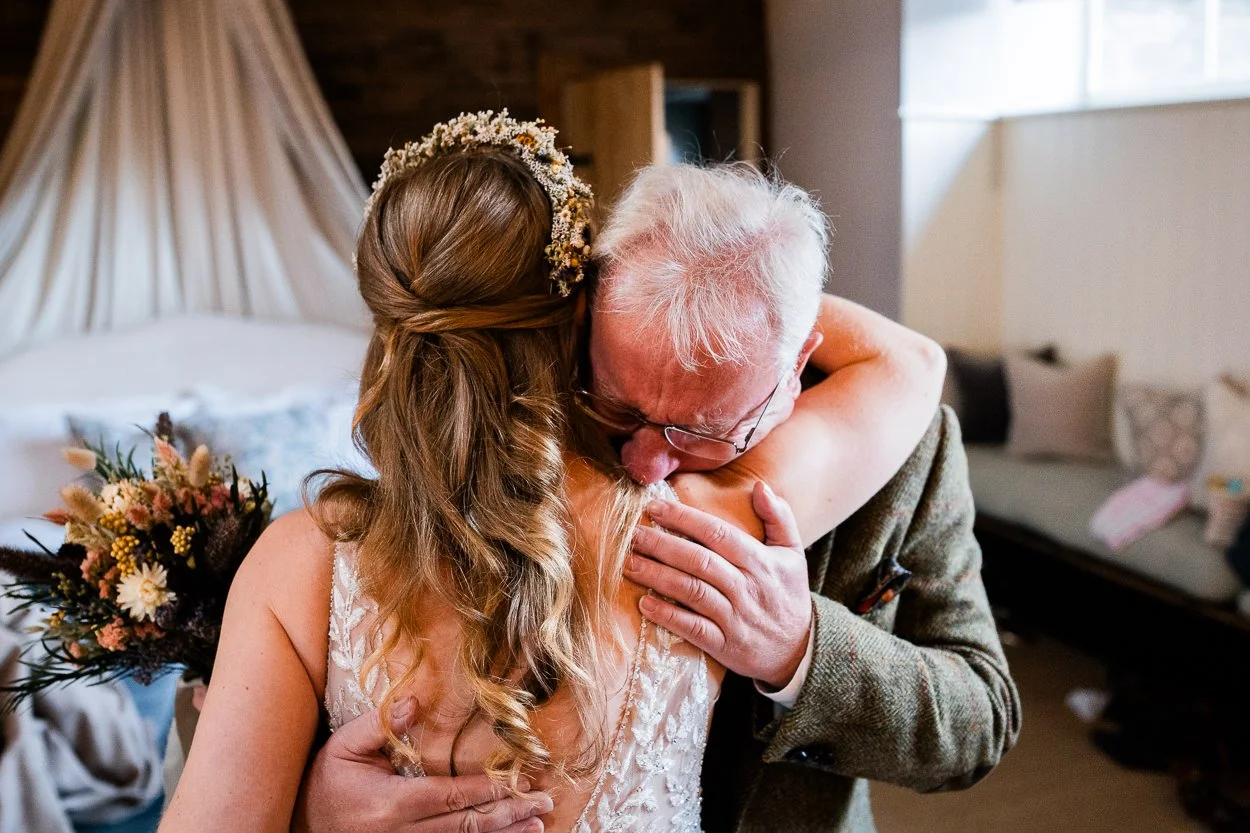 Father of the bride in tears hugging bride