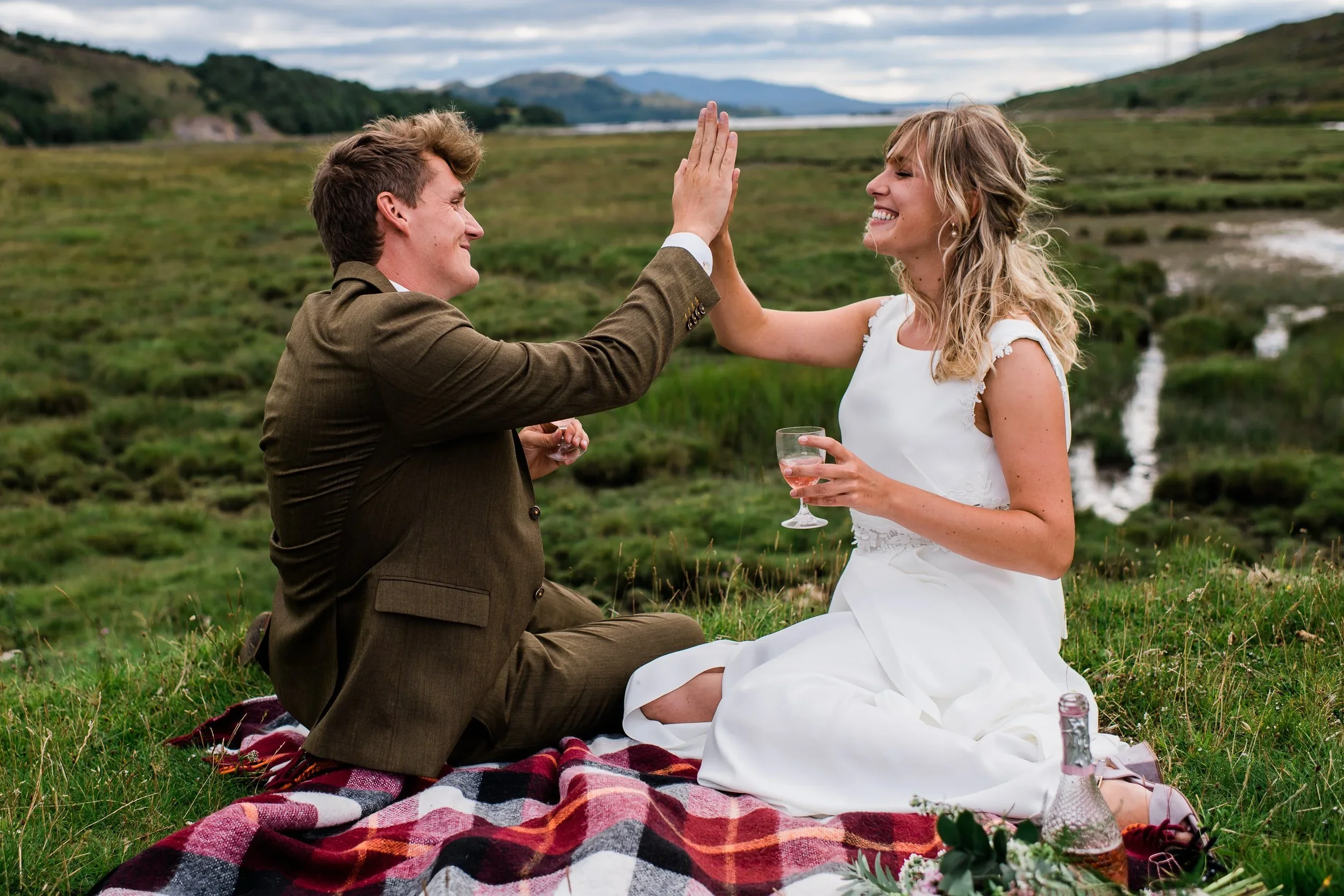 Bride and groom high five having a picnic at Torridon elopement