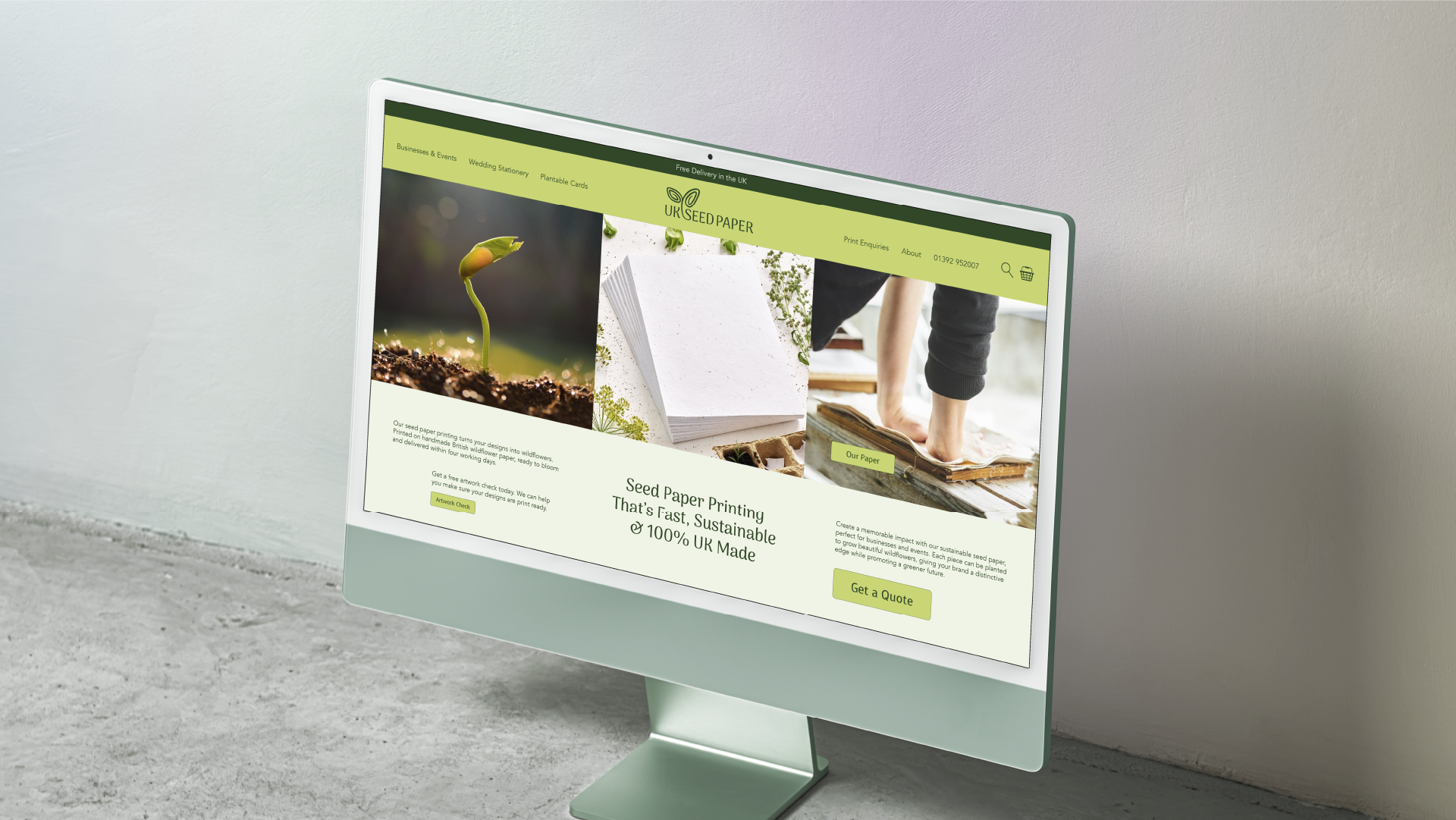 Computer monitor displaying a website for UK Seed Paper featuring images of a sprouting seed, stacks of paper, and a person working with paper.