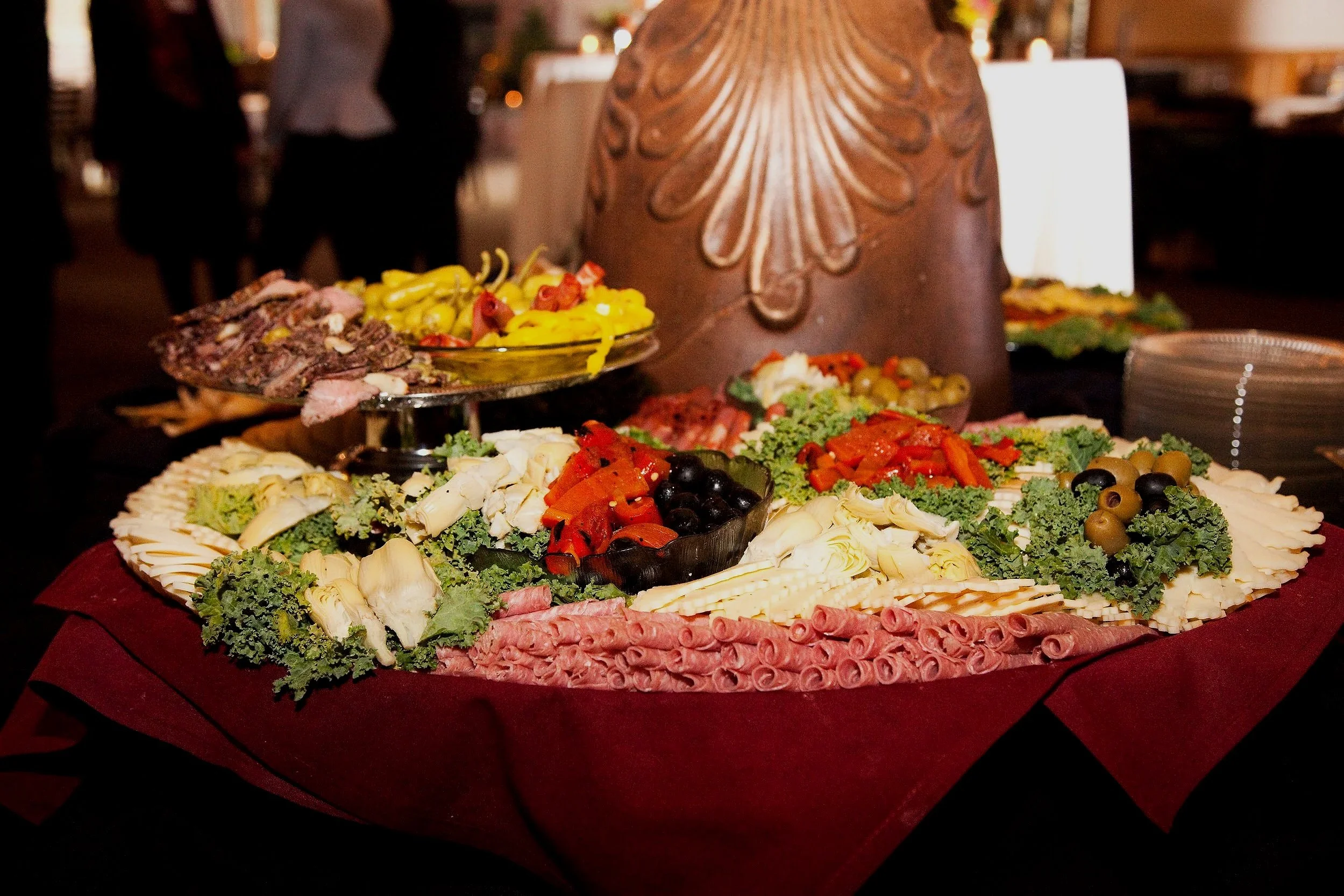 A charcuterie and vegetable platter with various cheeses, meats, olives, and vegetables on a table.