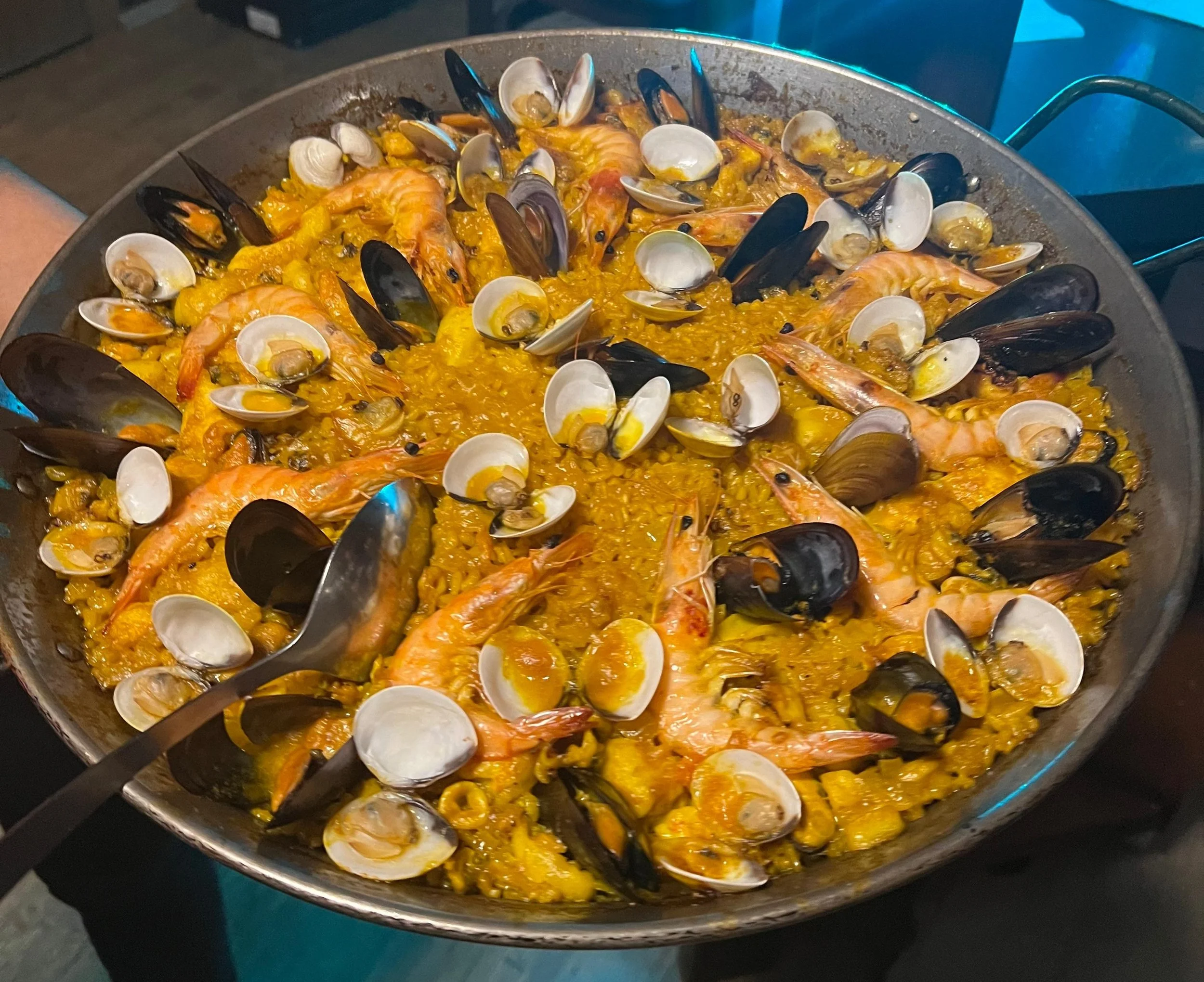 Paella mit Meeresfrüchten, einschließlich Garnelen, Muscheln und Tintenfisch, in einer großen Pfanne