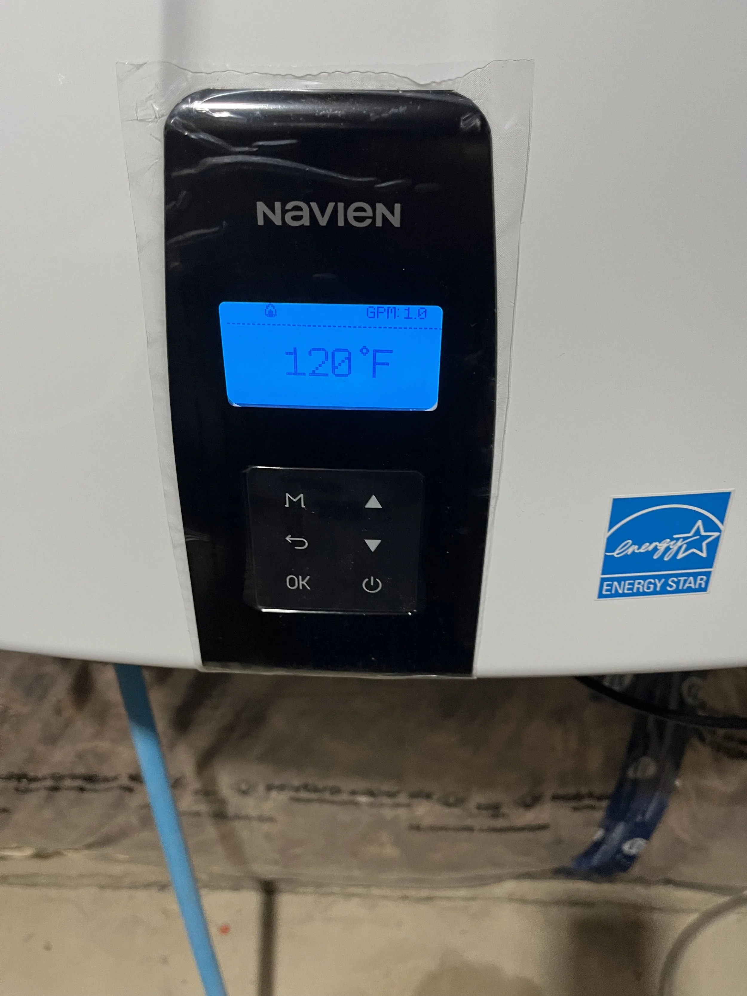 Close-up of a digital thermostat displaying 120°F with a blue backlight, mounted on a white surface, with energy star sticker below.
