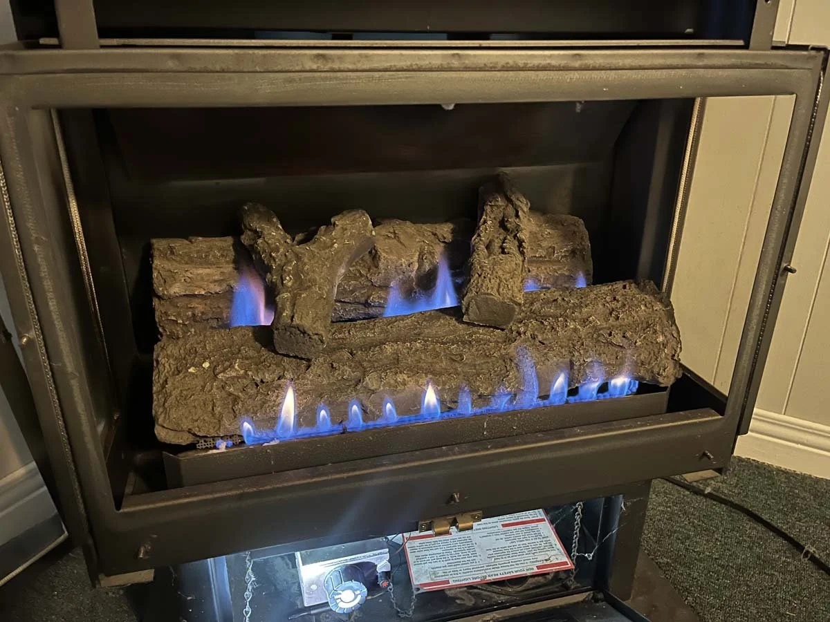 A gas fireplace with artificial logs and blue flames.