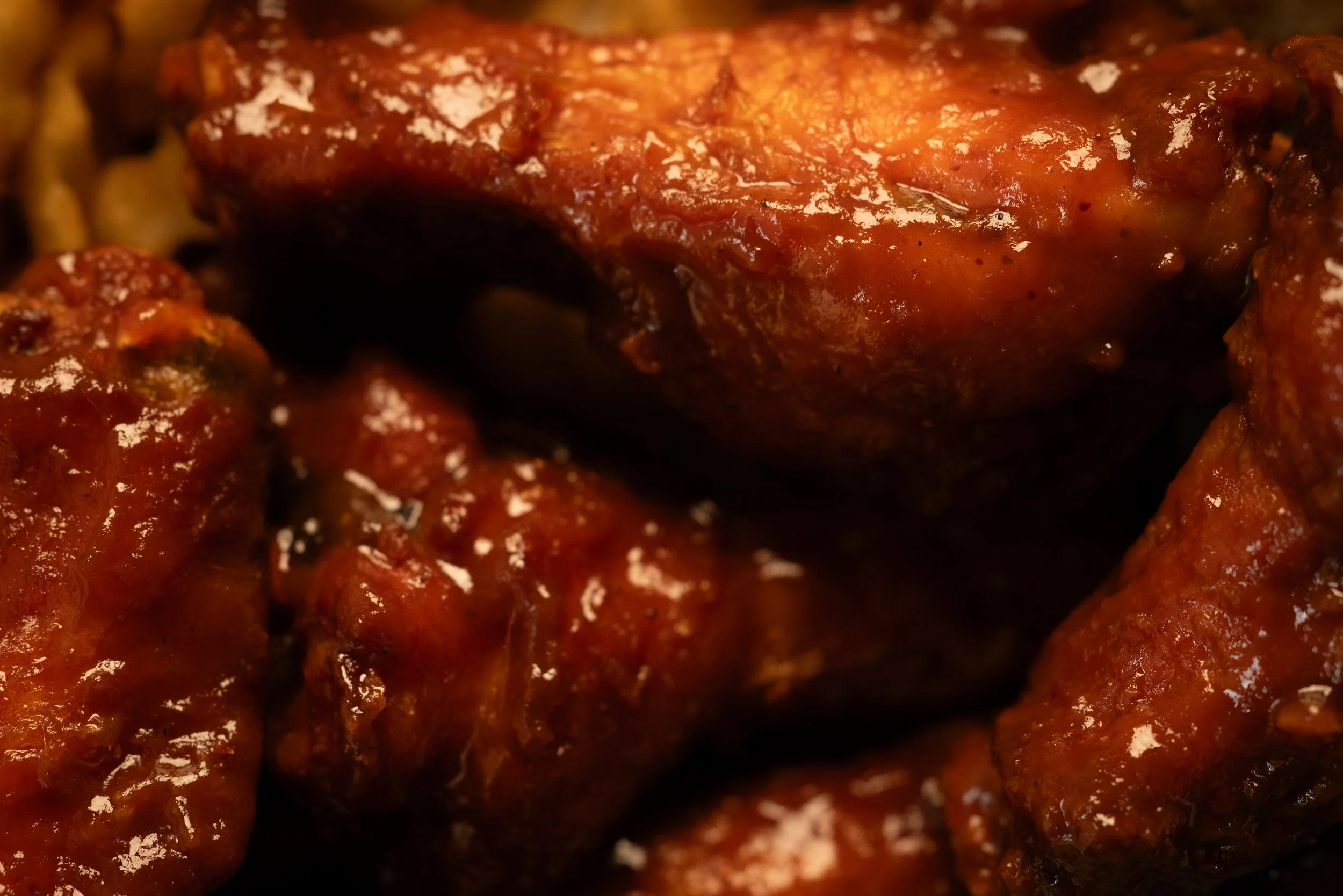 Close-up of glazed, cooked chicken drumsticks in barbeque sauce.