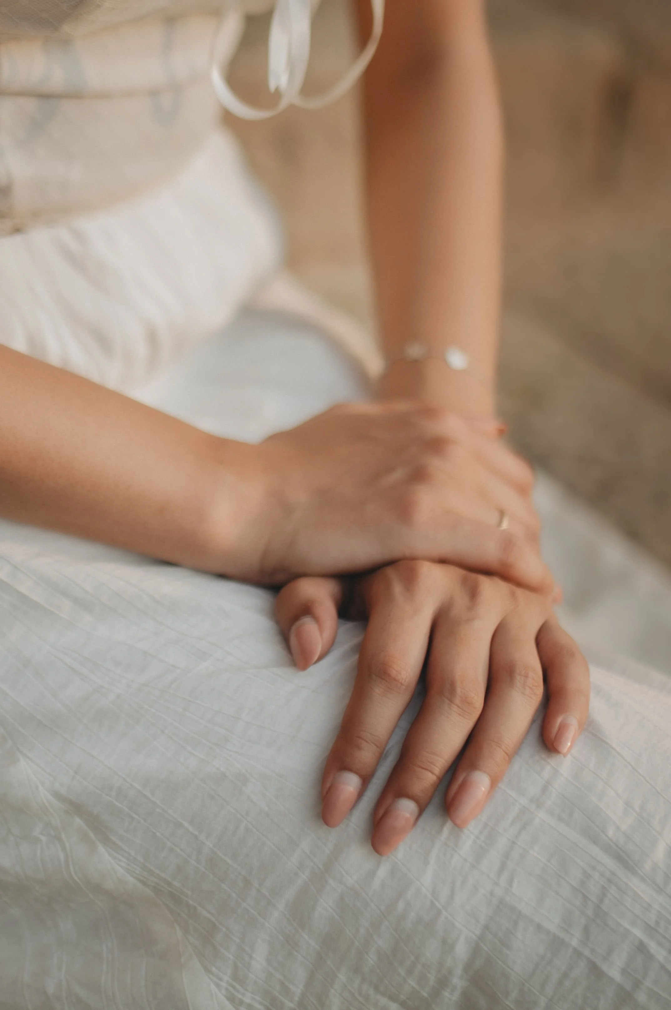 Close-up of a woman's hands resting in her lap, representing the somatic and body-level nature of attachment trauma stored in the nervous system.