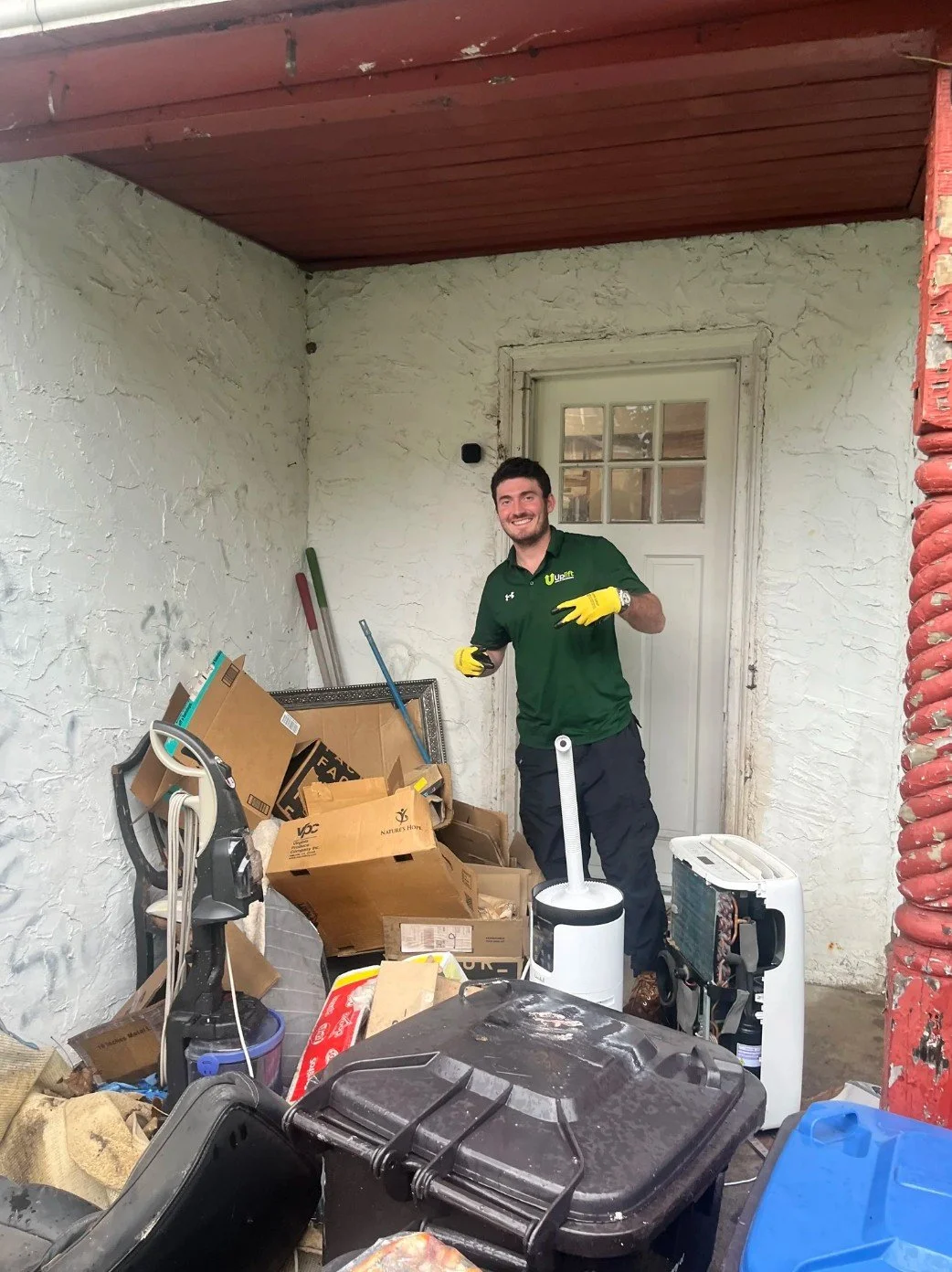 Richard, Uplift Junk Solutions founder, giving a peace sign after a successful junk removal job on a Philly porch.