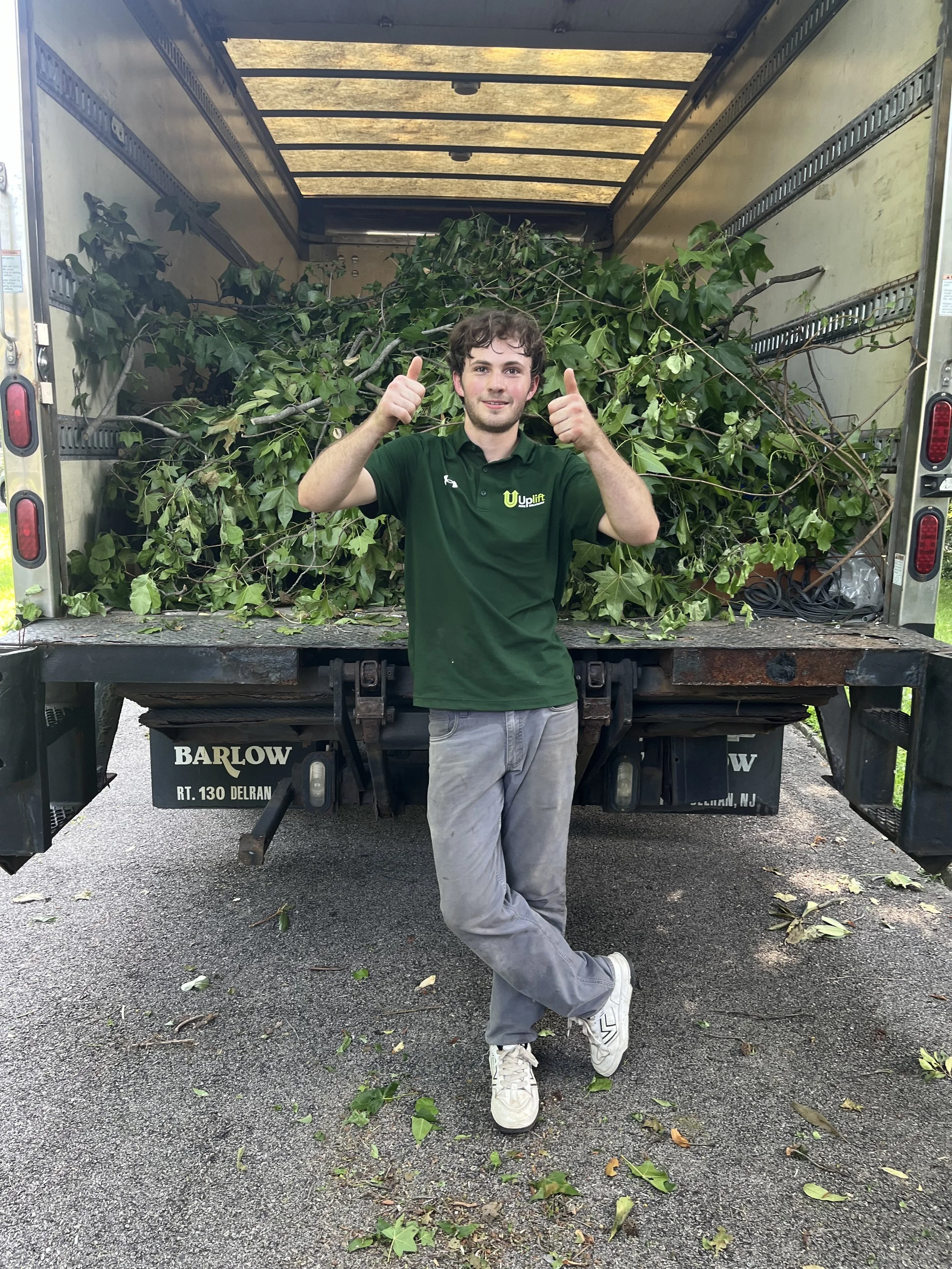 Uplift Junk Solutions team member giving a thumbs-up after removing yard waste in Chestnut Hill.
