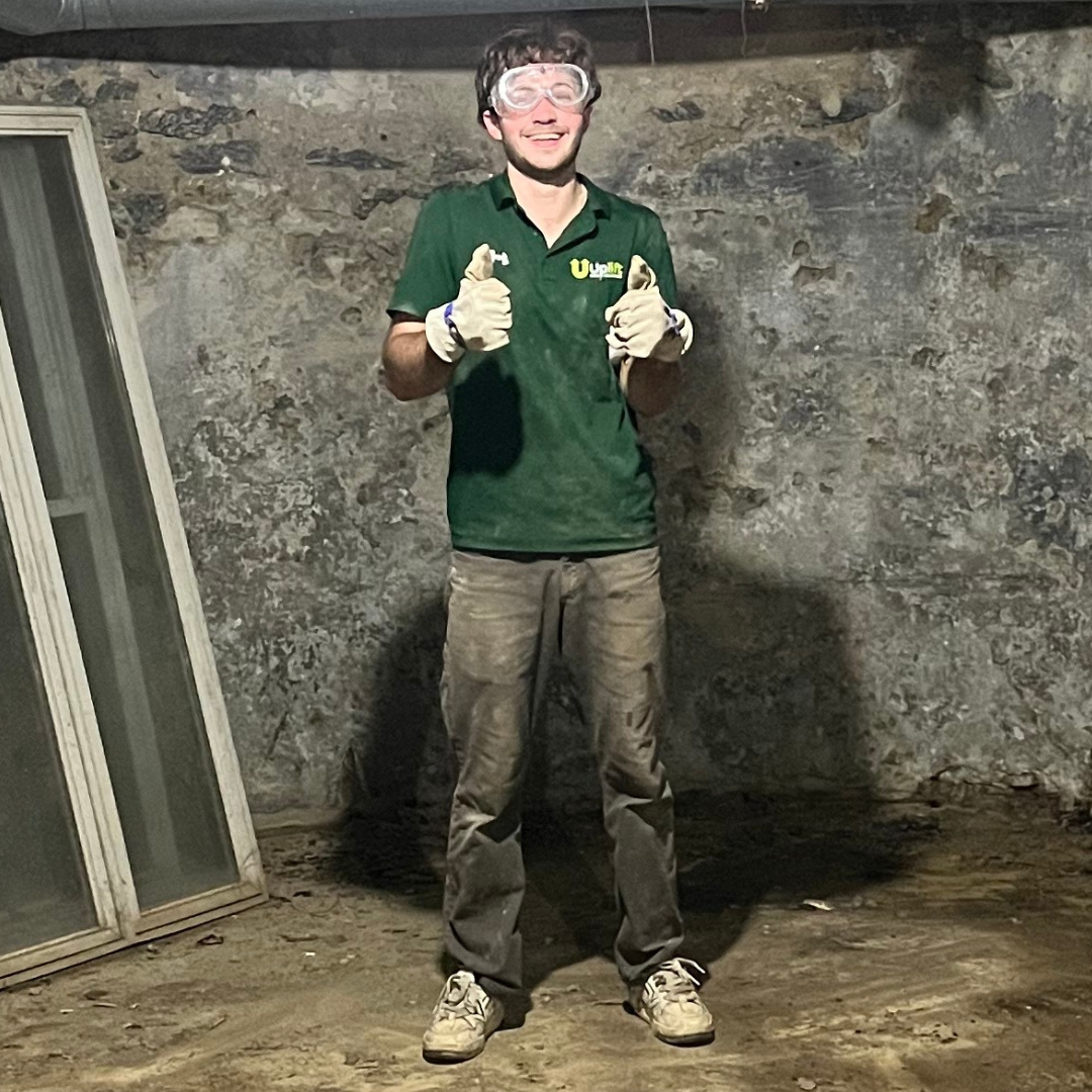 Tristan, Uplift Junk Solutions founder, wearing safety goggles and giving the two thumbs up in a basement clearout in the Main Line, PA.