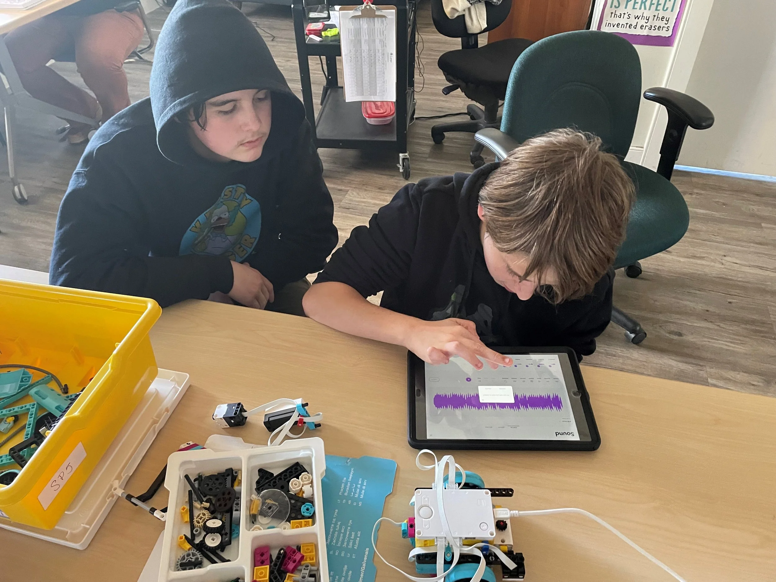 Two youth working at a desk on a tablet
