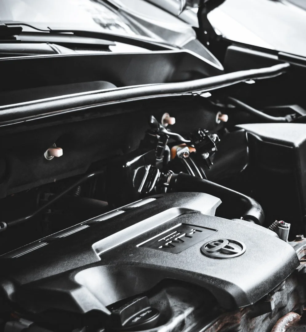 Close-up of a Toyota car engine in a vehicle's engine bay, showing the engine cover and components.