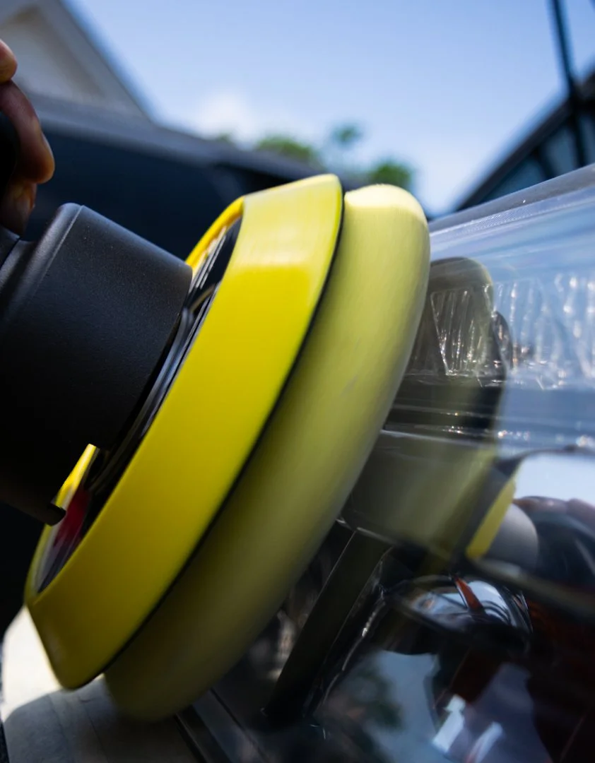Close-up view of a yellow and black robotic or industrial device with a clear plastic cover and metallic components, outdoors with a blue sky and trees in the background.