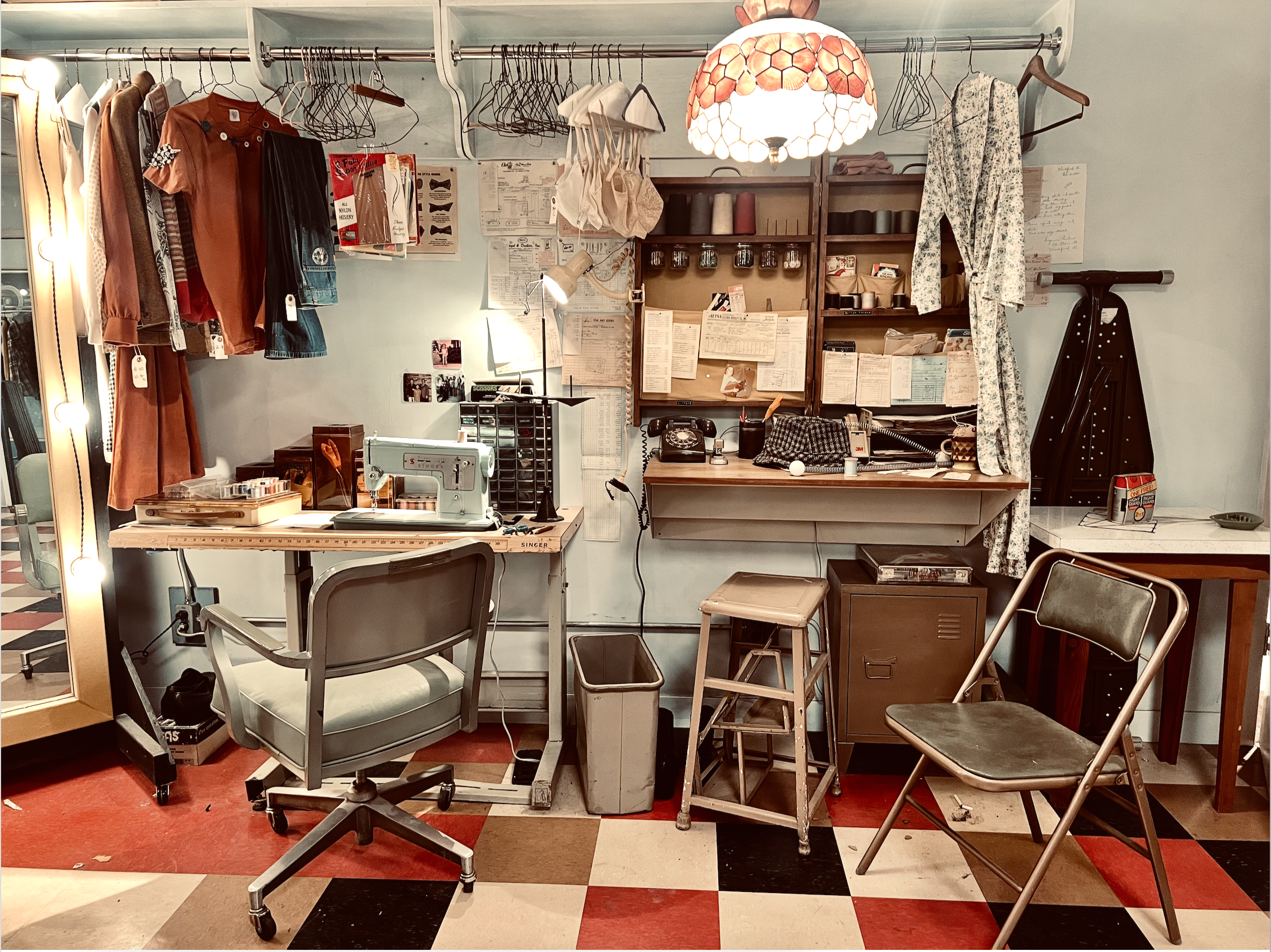 Inside Saturday Night movie  vintage sewing and craft dressing room with clothing, sewing machine, office chairs, and various crafting supplies on wall shelves and desk.