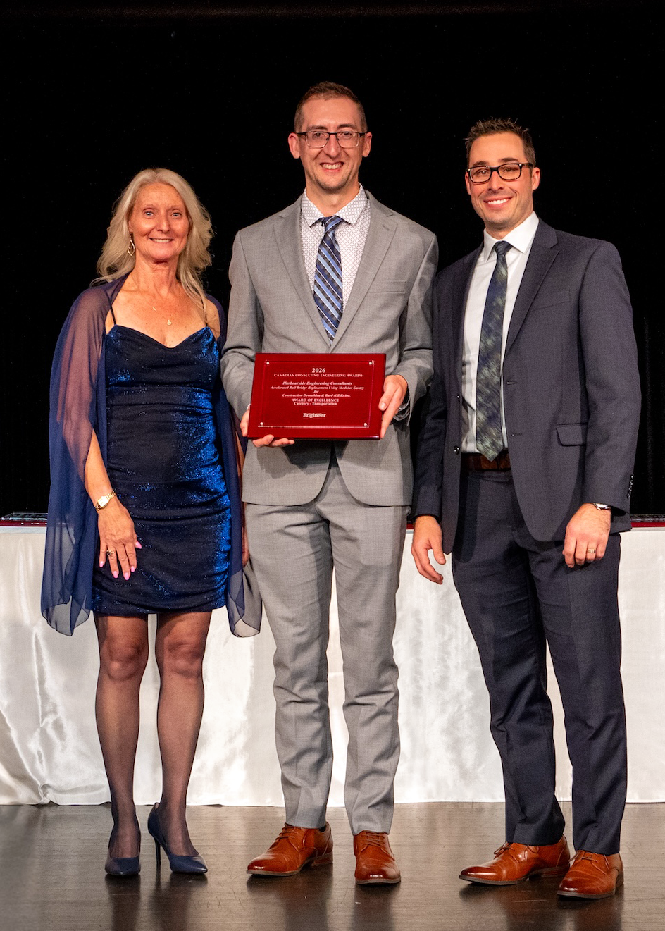 Calvin MacAulay and Wade Pottie on stage accepting the award for their work on the Etobicoke Rail Bridge Replacement. One of the awards CCE representatives stands on stage with them.