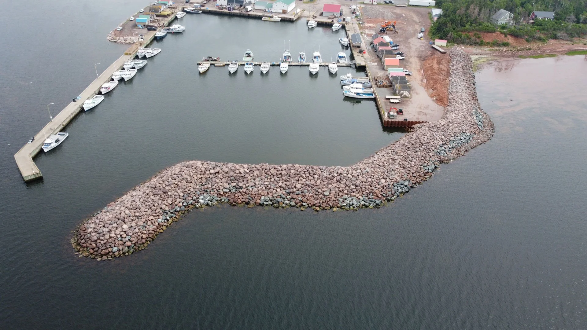 An aerial view of the new breakwater structure at Red Head Harbour in 2025. Several small craft vessels are moored to the new floating dock elements.