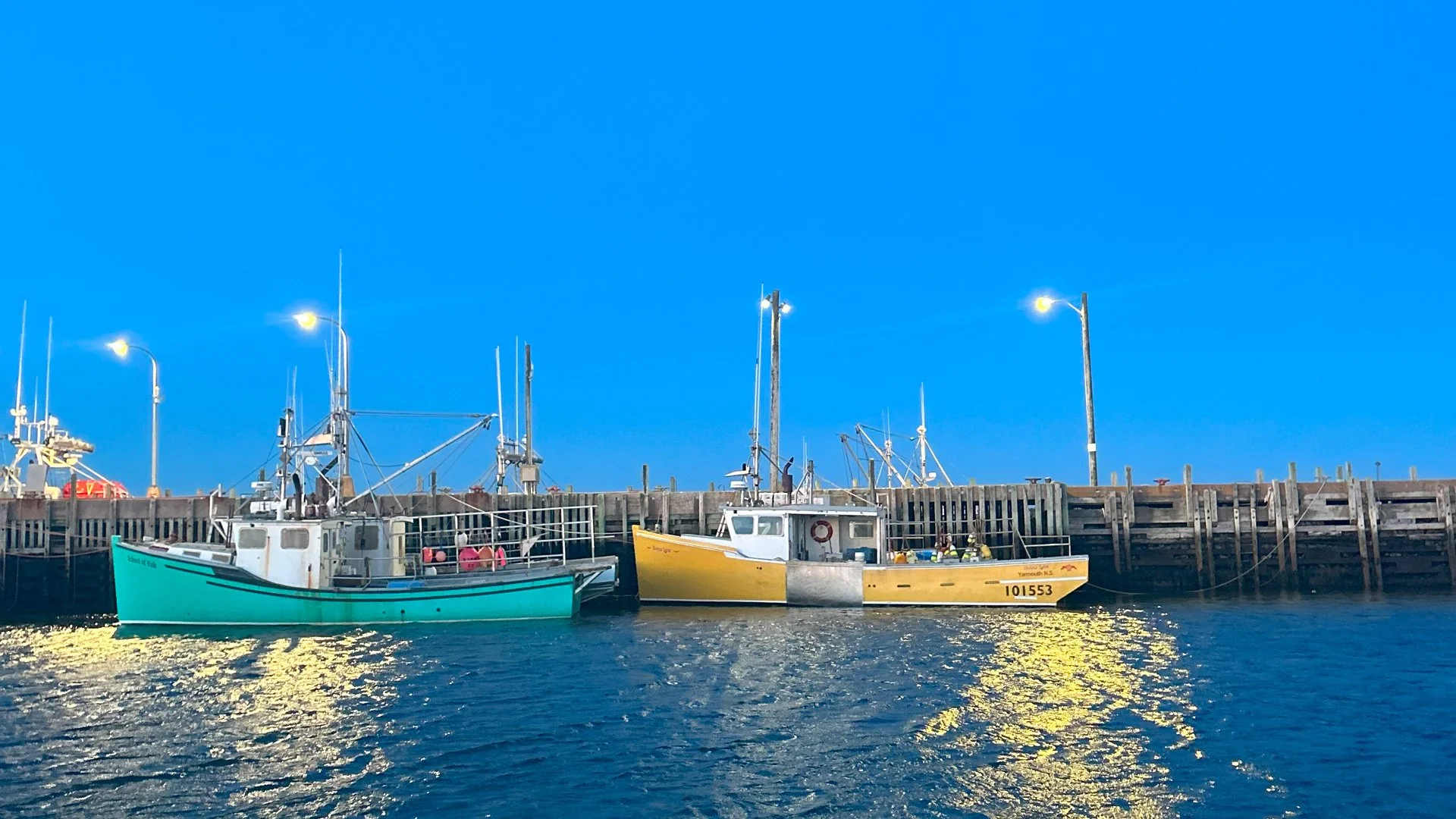 The sky darkens as evening approaches in Freeport, Nova Scotia. Two brightly coloured vessels are tied up, as the investigation takes stock of the harbour infrastructure conditions.