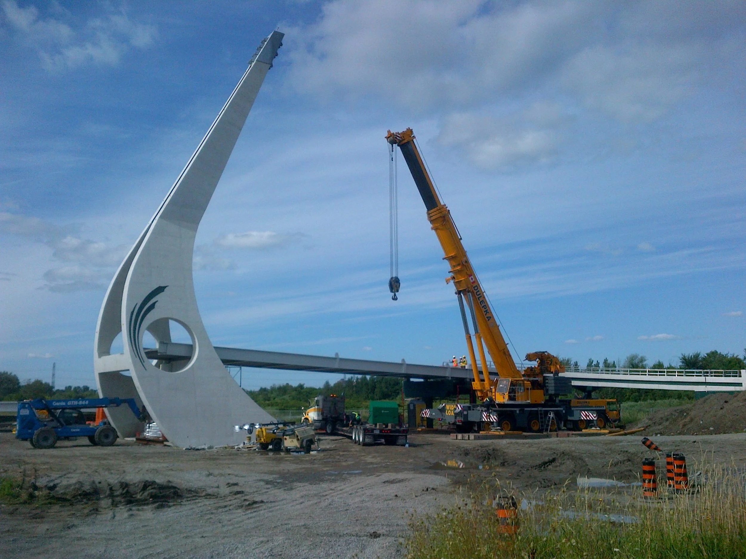 A crane can be seen on the construction site of the future Juno Beach Memorial Bridge. The tower is in place, and the spans to one side are being erected.
