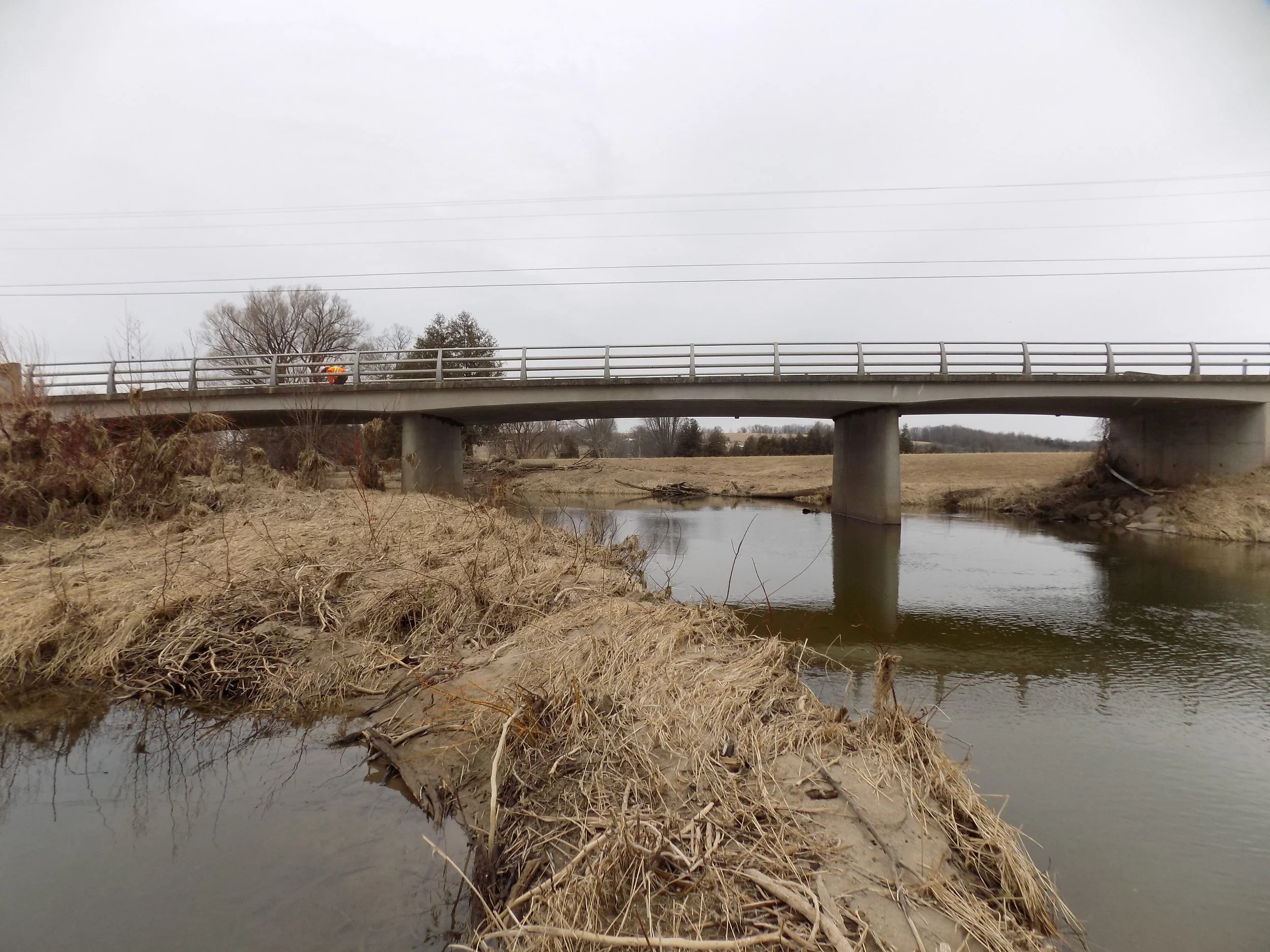 Concrete piers just from the water, supporting this bridge in Meaford Ontario. The foreground is dominated by dried grasses and water.