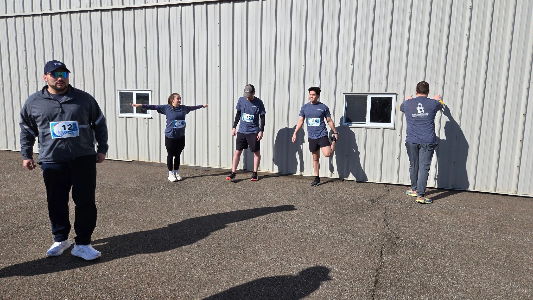 The Harbourside Engineering PEI team getting ready for the 5km Charlottetown YYG Runway Run. Hailey performs her signature “Airplane Stretch”.