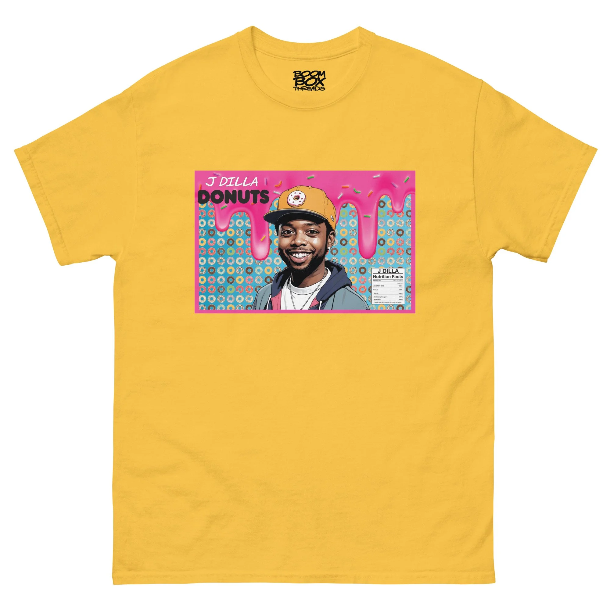 Yellow T-shirt featuring a colorful pop art style illustration of a smiling man wearing a baseball cap, with pink dripping icing and sprinkles in the background, and the words "J DILLA" and "DONUTS"