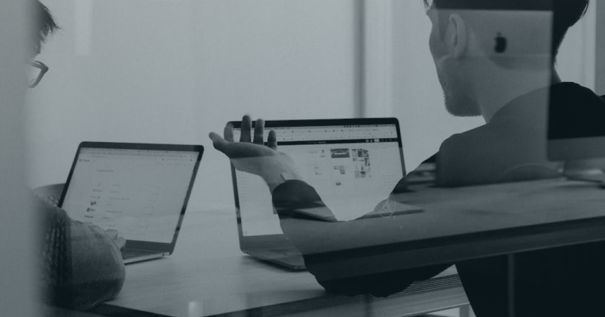 Hands gesturing over two laptops displaying a custom Squarespace website design for a UK small business