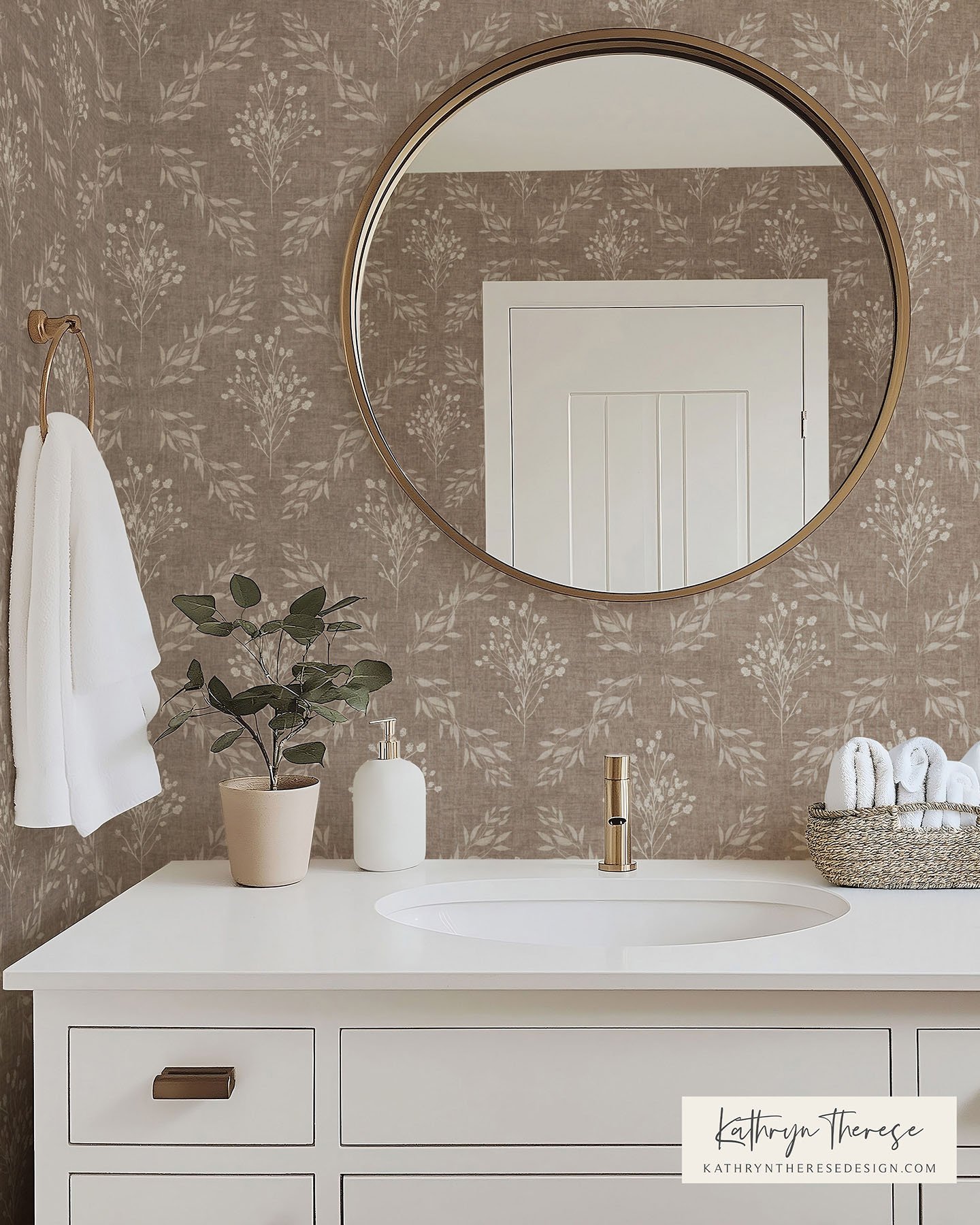Bathroom vanity with a large round mirror, potted plant, soap dispenser, and rolled towels in a basket, with a patterned wallpaper background.