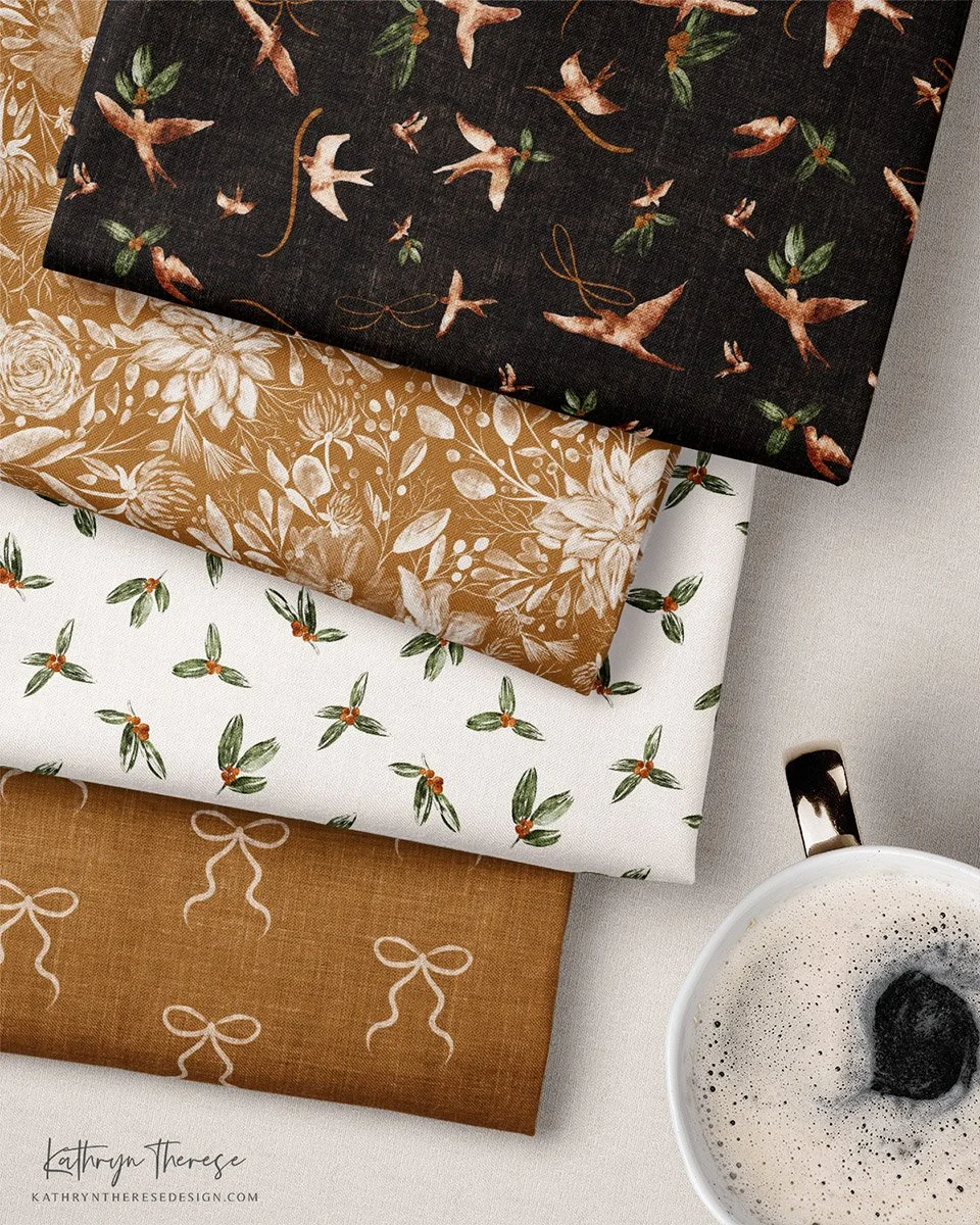 Four folded pieces of fabric with various holiday-themed patterns, placed on a white surface next to a cup of coffee.
