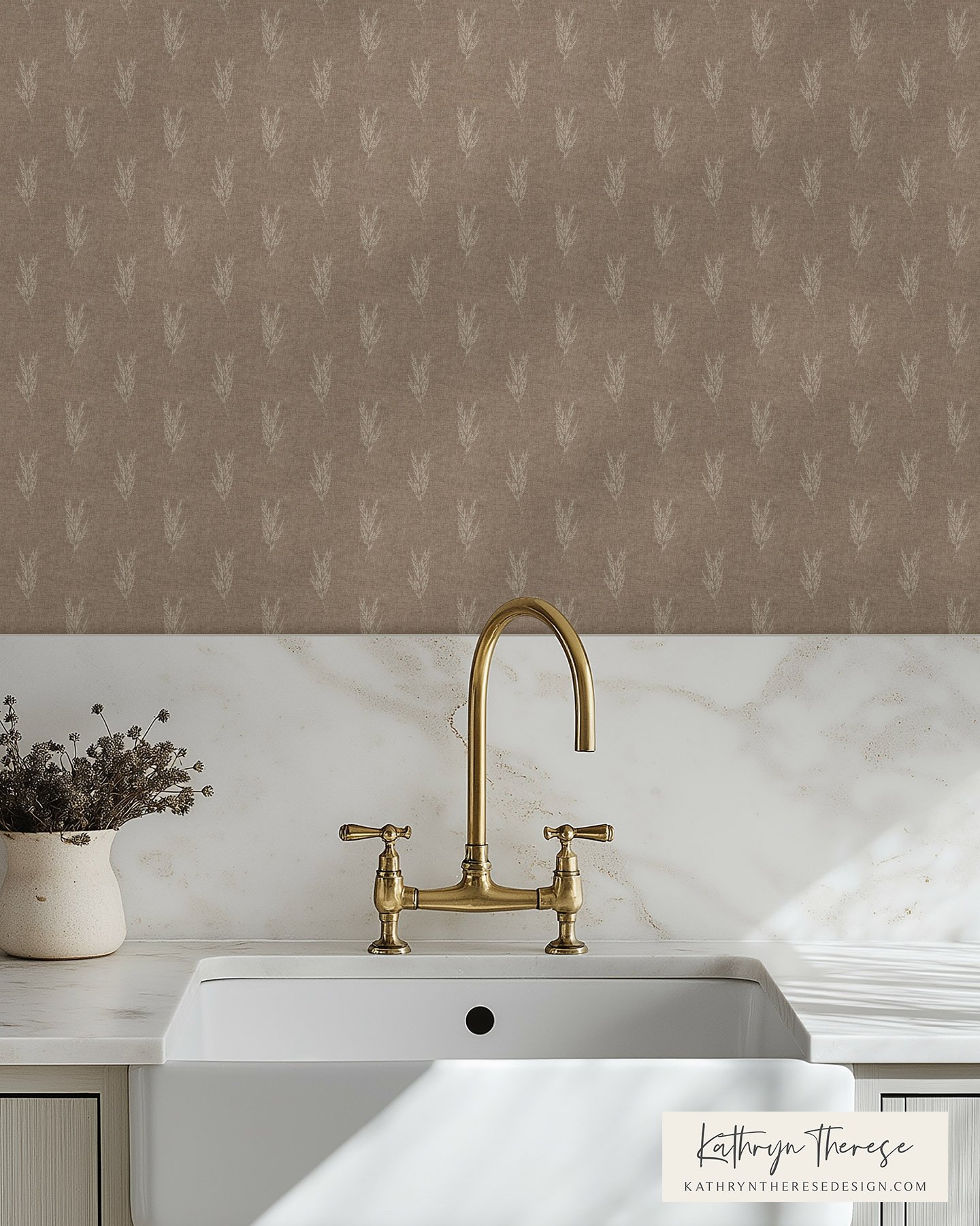 Close-up of a kitchen sink with a golden faucet, white countertop, and a small potted plant with purple flowers on the left. The background features a beige backsplash with a subtle leaf pattern.