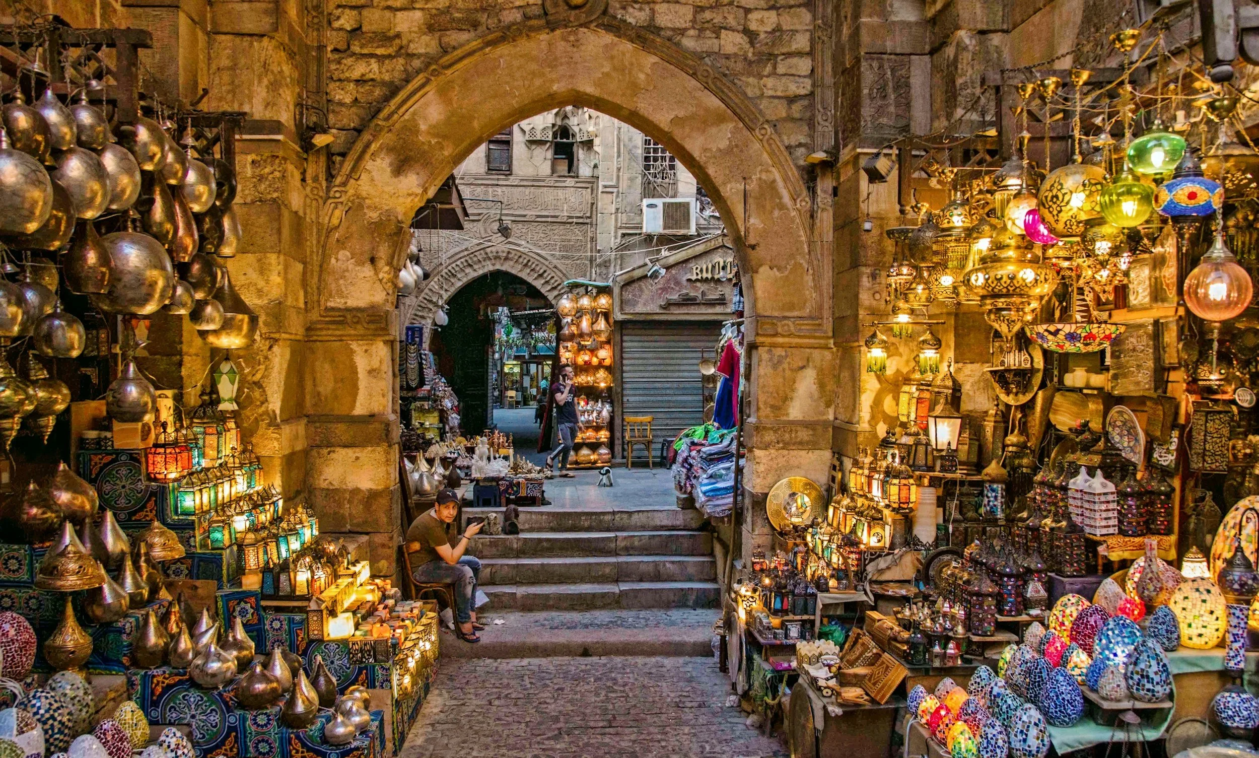 Marché avec étals de lanternes colorées et lampes en verre, dans une rue pavée ancienne en Orient.