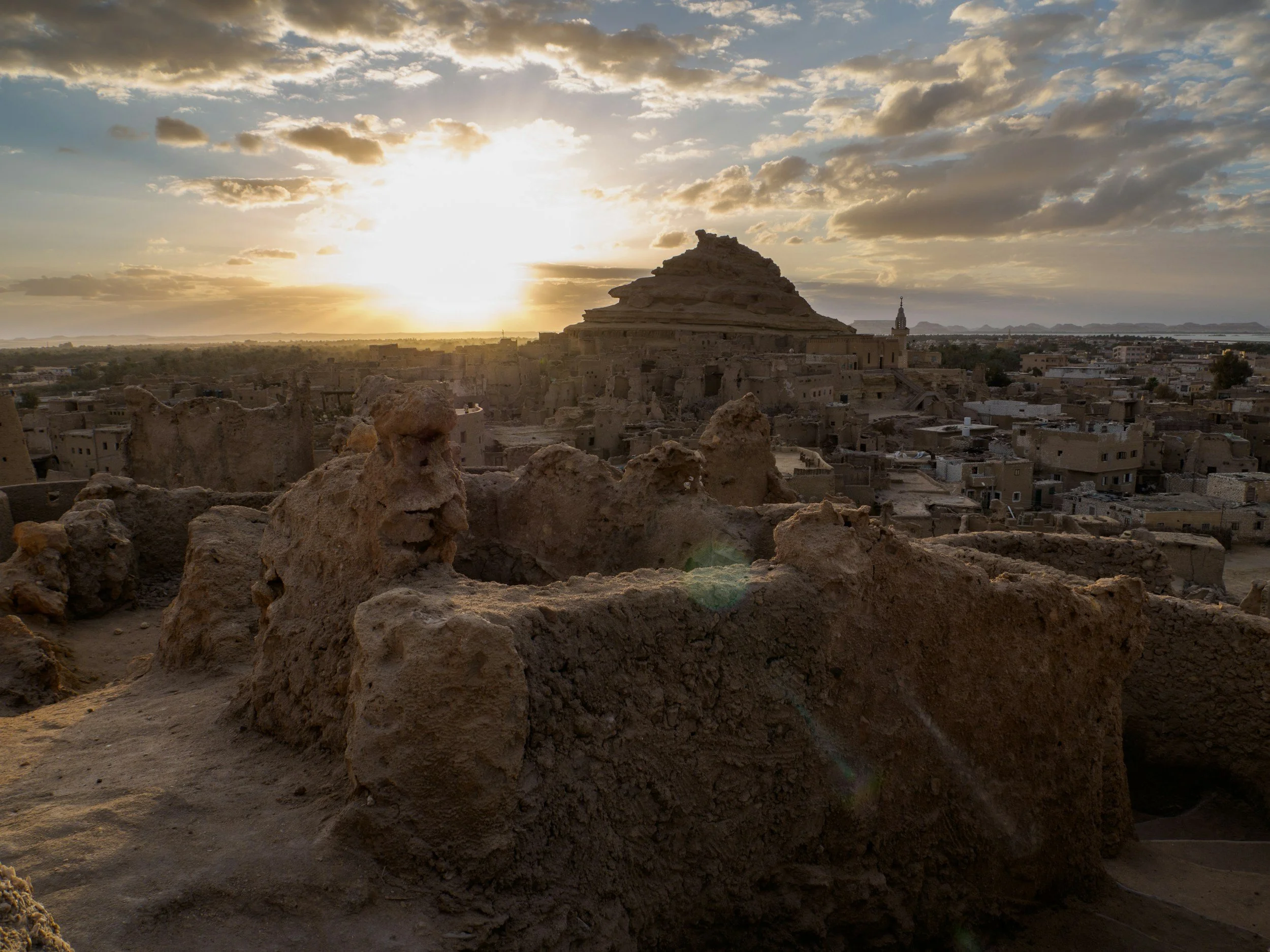 Vue d'une ville ancienne avec des bâtiments en adobe, un sommet en pyramide, au coucher du soleil.
