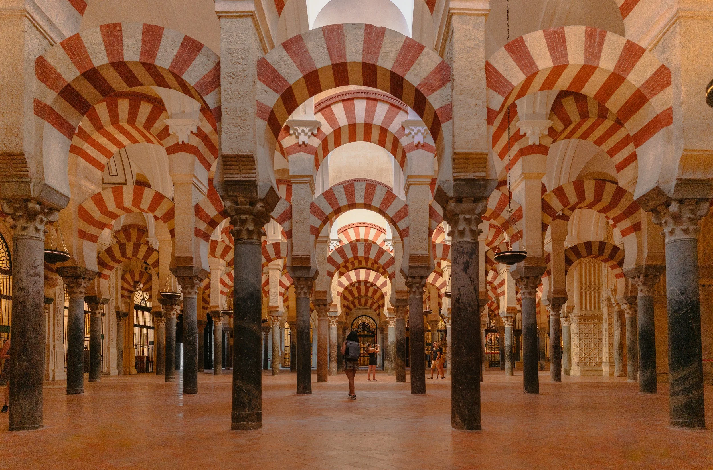 Intérieur d'une mosquée avec des arches à rayures rouges et blanches et des colonnes en marbre noir.