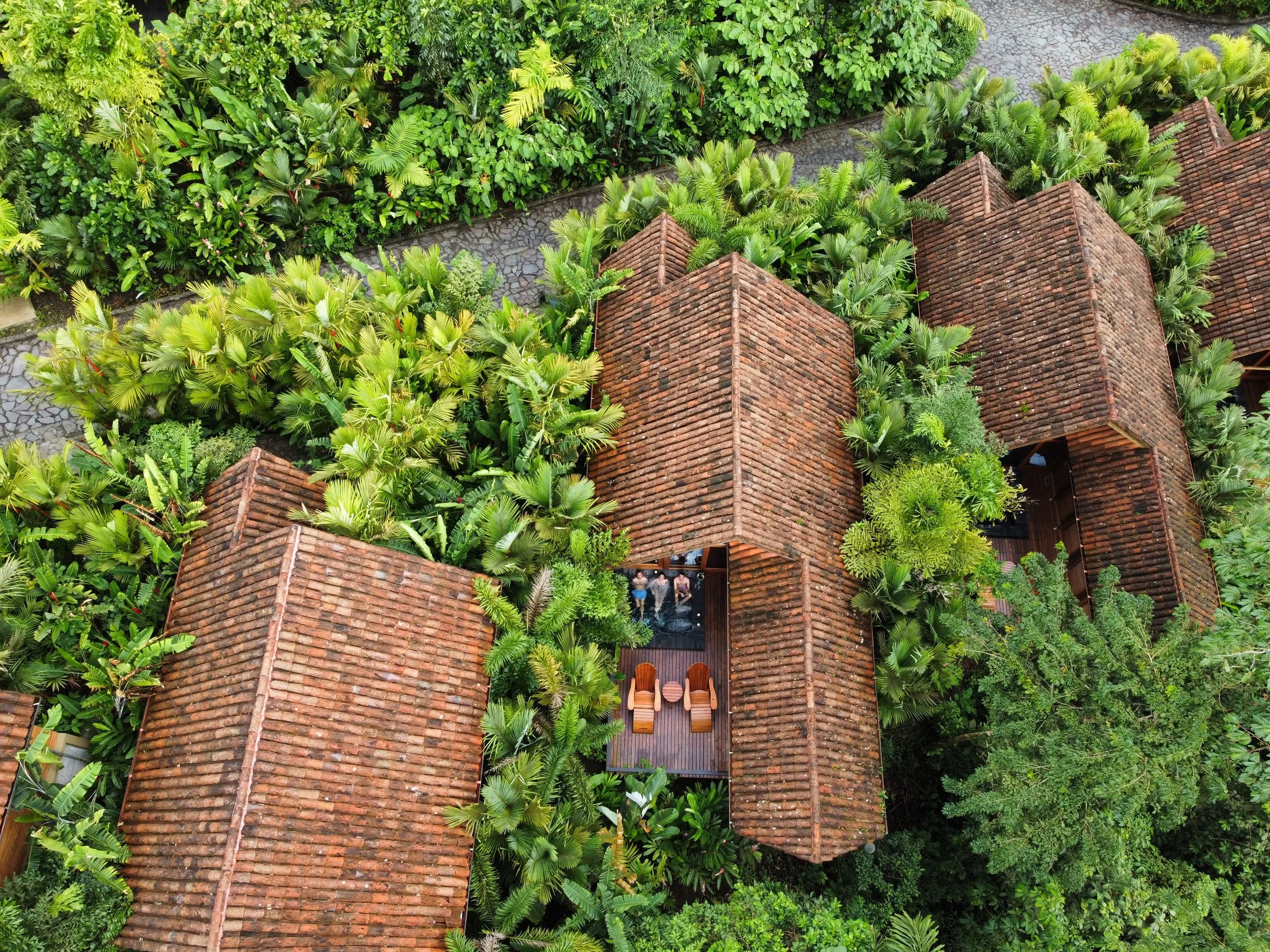 Vue aérienne de bâtiments en briques rouges entourés de végétation tropicale dense