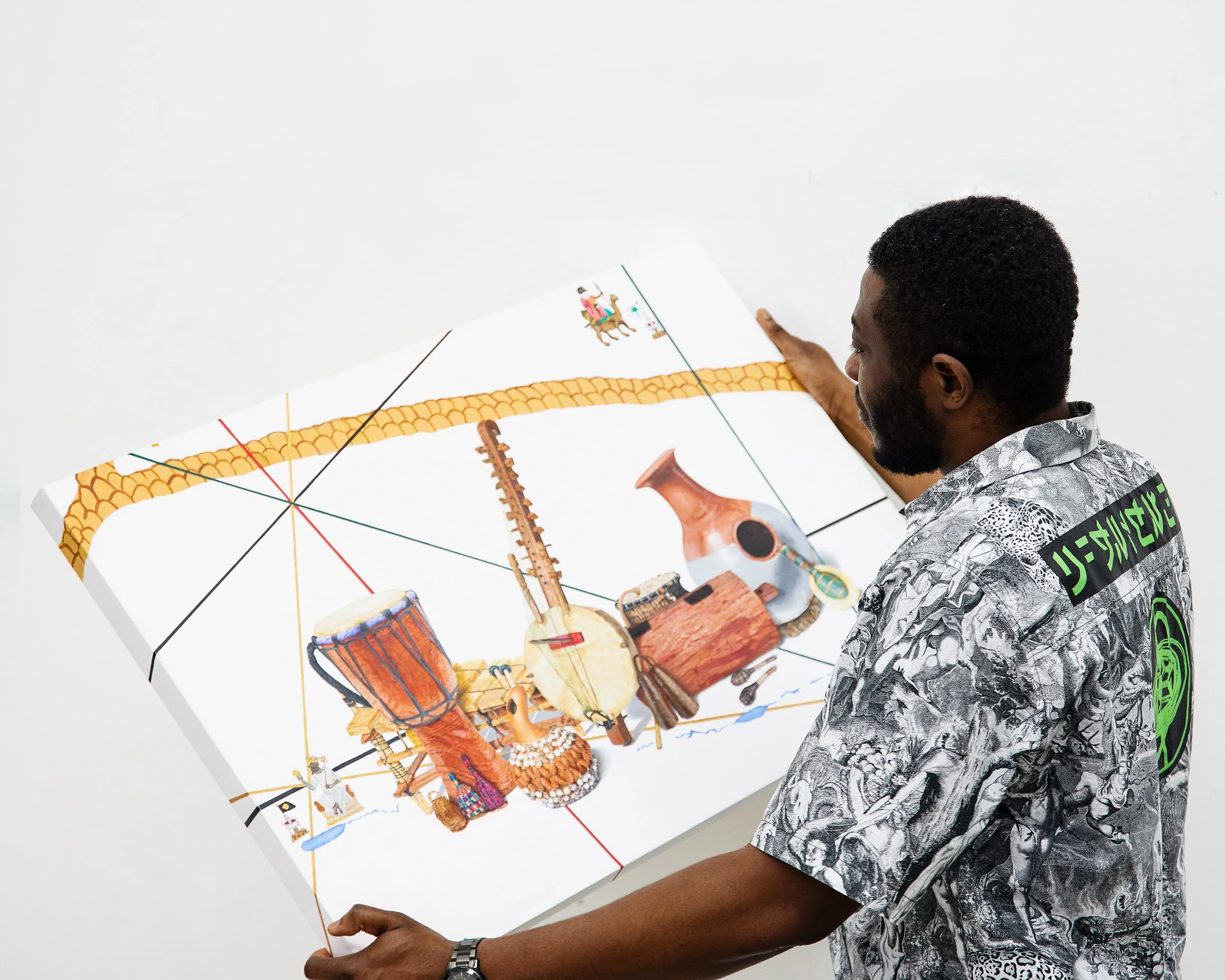 Chiedu holding his painting called "Tetris - Roots sound", which was made as homage to his Dad and resonates with the importance of community building.
