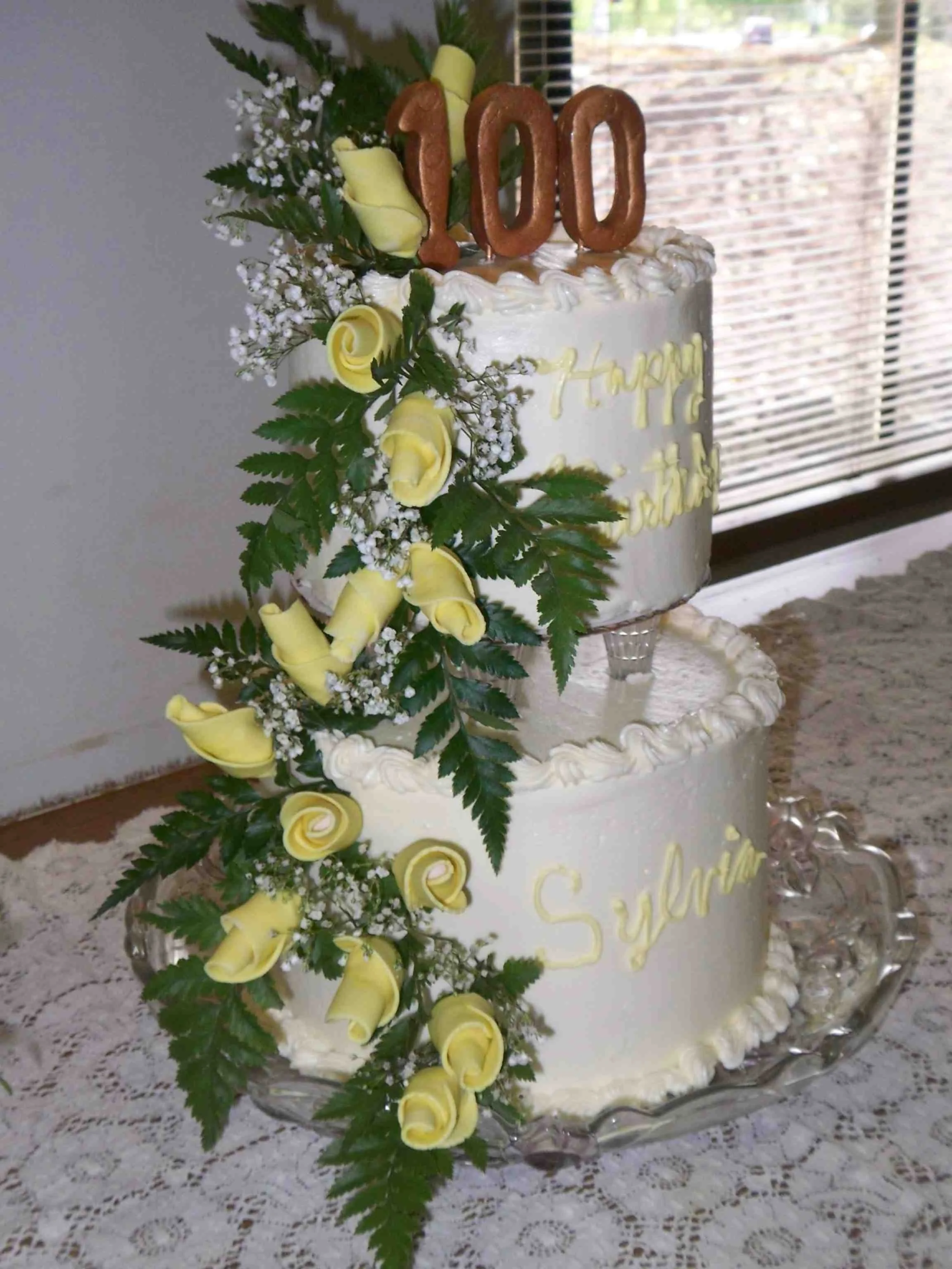 100th Birthday with Sugar Porcelain Cascading Yellow Roses from Top of the Two Tier Buttercream Frosted Crystal Pillar Separated Cake Fresh Greens and Fondant One Hundred Brushed With Metallic Old Gold Sugar