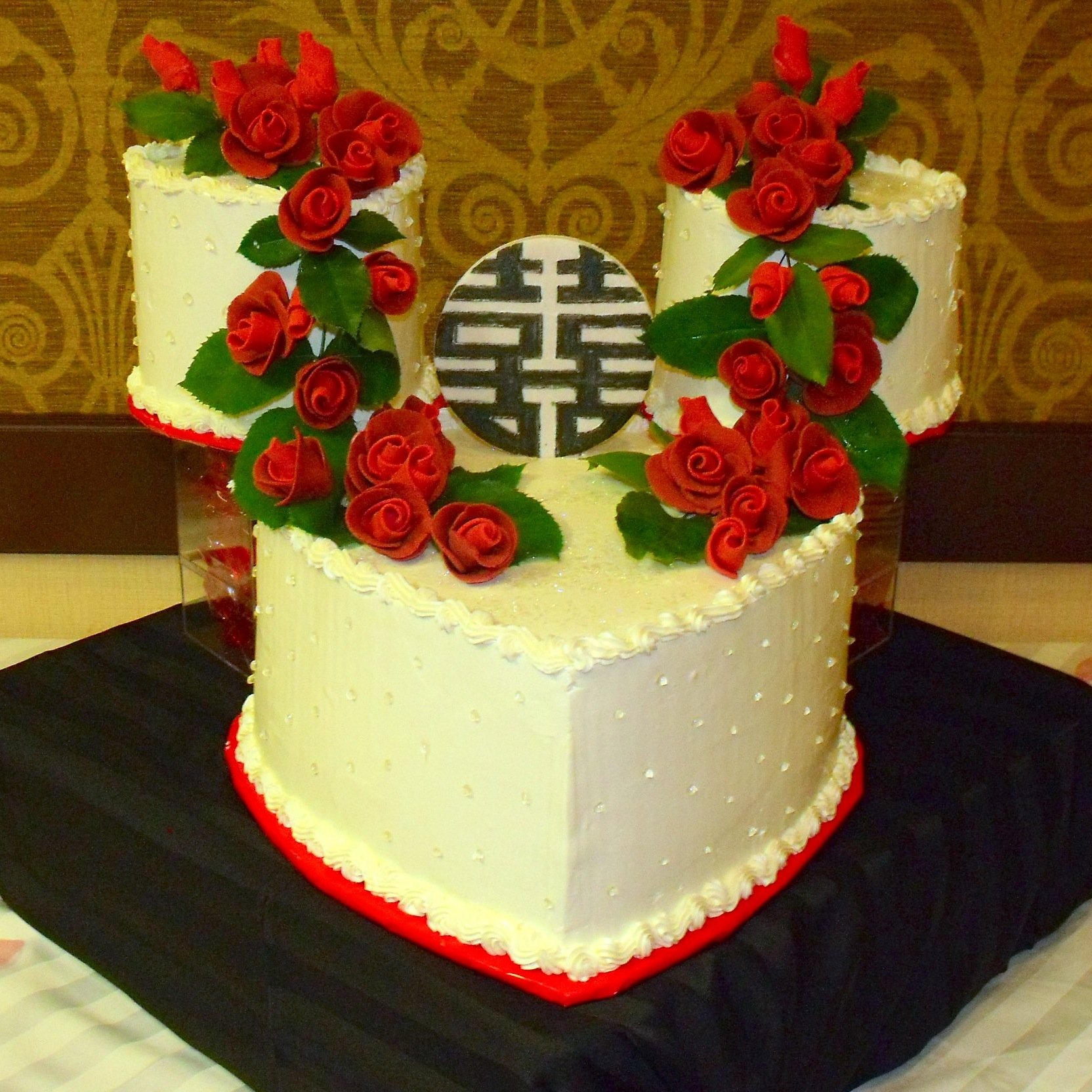 Romantic Buttercream Frosted Tiered Wedding Cake Two Round Crystal Supported Round Tiers Behind the Heart 
Shaped Main Cake Buttercream Piped Top and Bottom Borders Clear Piped Pearls on Cake Sides Sugar Porcelain Asian Graphic Cascading Red Sugar Po