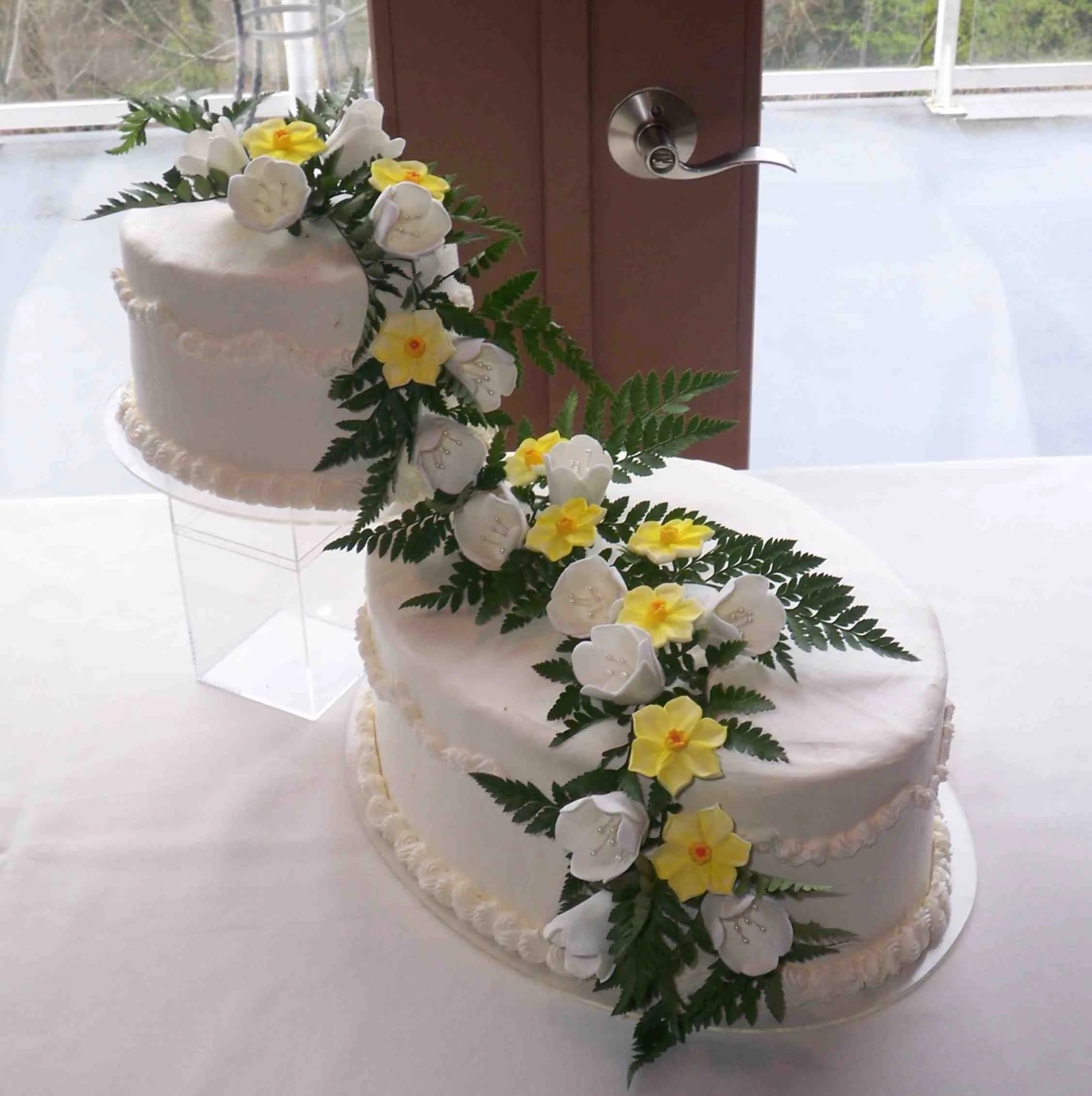 Oval Buttercream Frosted Offset Wedding Cake Waterfall Cascade Sugar Porcelain White Tulips Daffodils Set With Fresh Greens