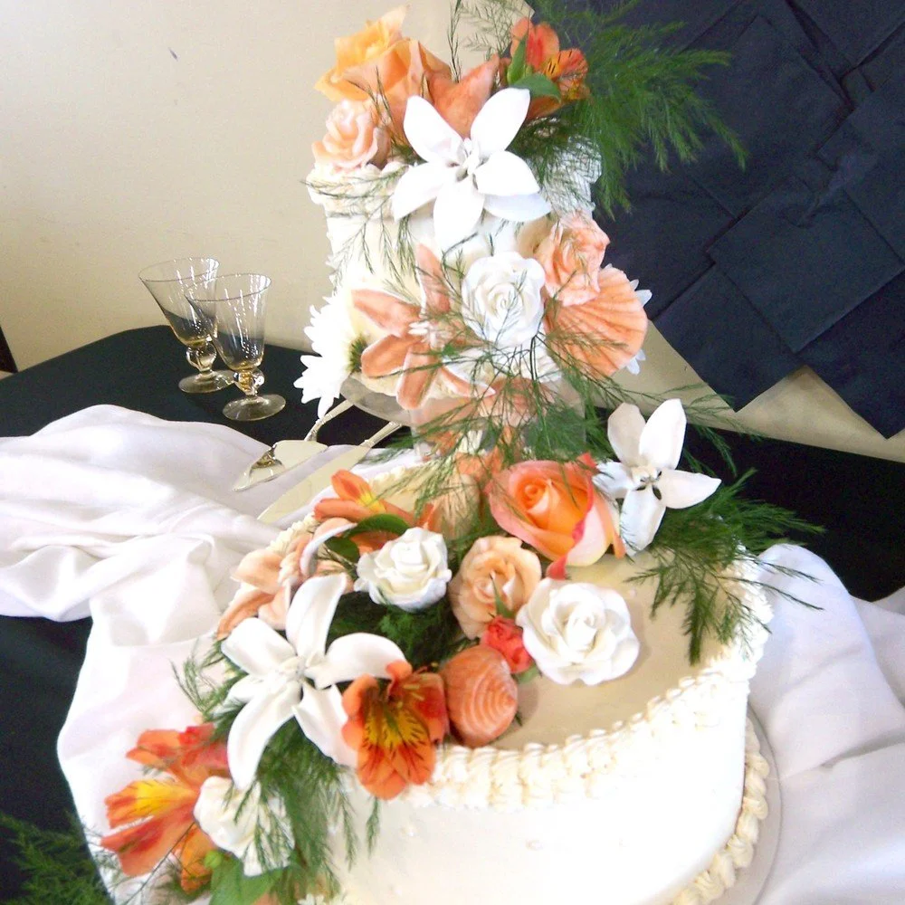Two Tier Round French buttercream frosted wedding cake sugar porcelain white full open Roses Stargazer Lilly orange sugar dusted rose fresh flowers asparagus greens 