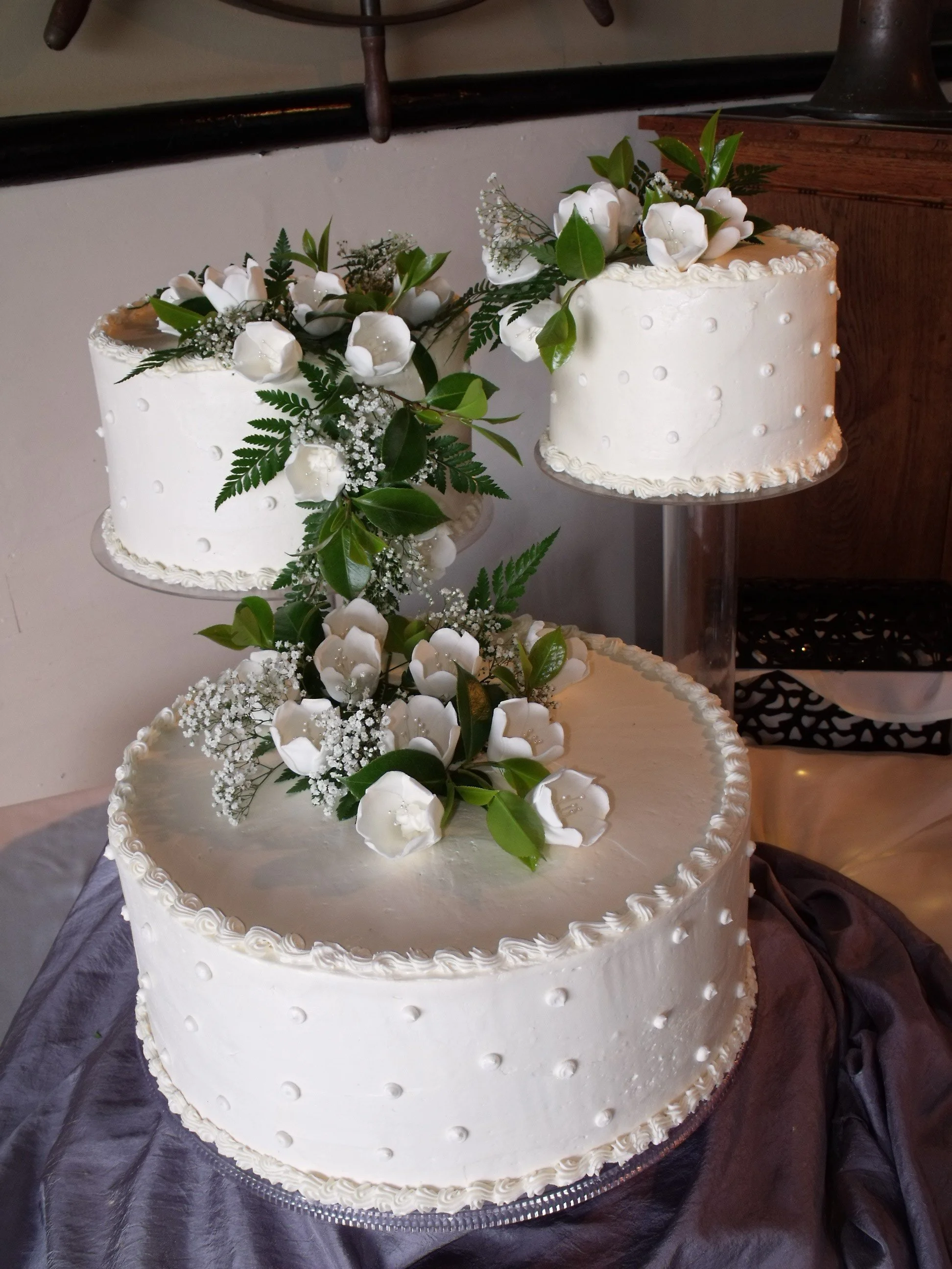 Three Separate Tiers Crystal Uplifted Wedding Cake in Ivory Buttercream Frosted Round Cakes Piped Pearl side decor Cascading Arrangement of White Tulips with Fresh Greens