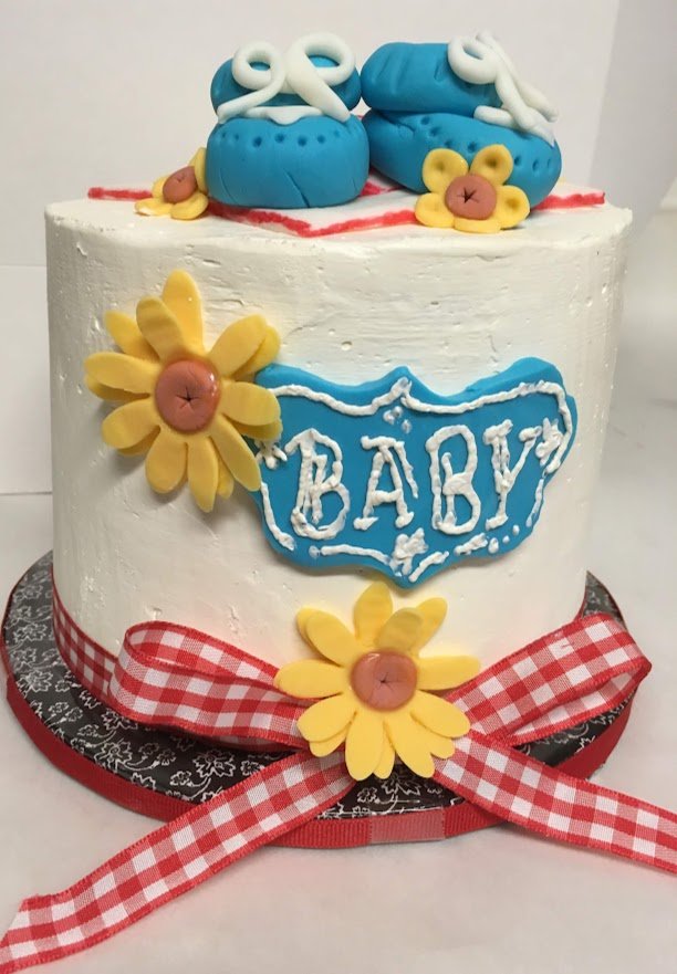 Baby Reveal Cake Fondant Booties Fondant Daisies and Baby Emblem Red Checkerboard Bottom Ribbon and Bow Black Wrapped Bottom Board with Red Ribbon Side