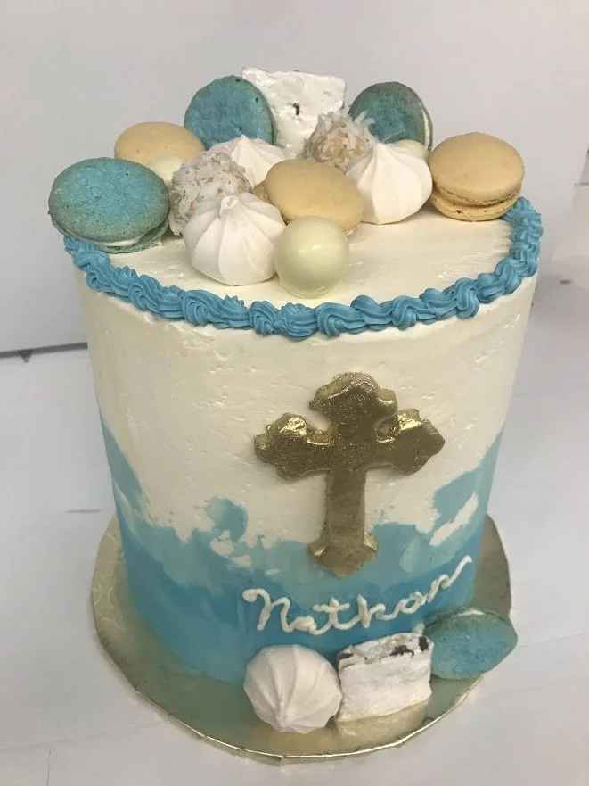 Smooth Side Buttercream Cake Hand Applied blended Painted Colors Gold Sugar Metallic Fondant Cross Scattered Macarons Egg White Puffs Nougat Chocolate Balls on Gold Wrapped Board