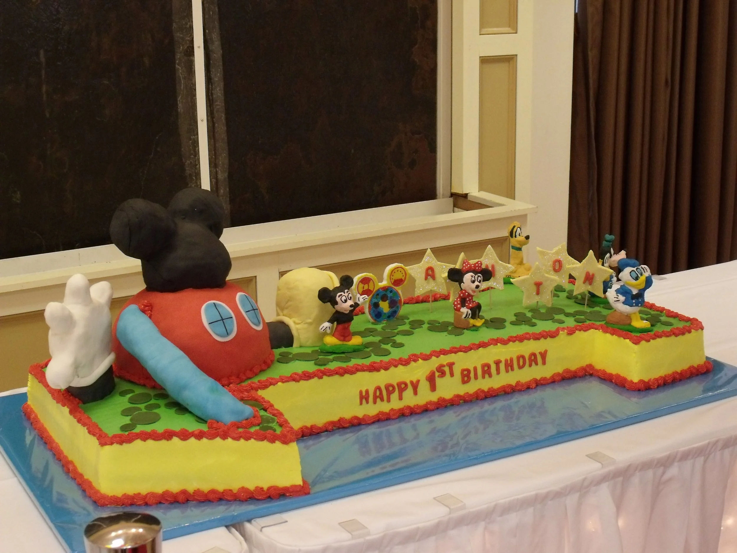 Three and a Half Foot Baby's First Birthday Sheet Cake Colored Buttercream Frosted Sides and Top Fondant Covered Mickey's Play House Fondant Mickey Shaped Path Stars Playhouse Emblem and Frosting Painted Sugar Mold Characters  