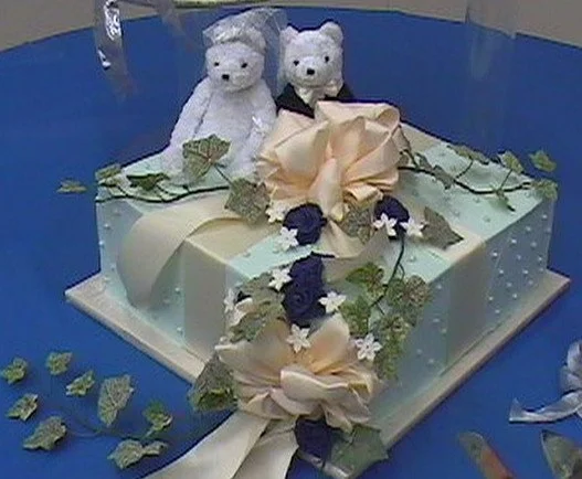 Wedding Cake Buttercream Frosted Decorated as Gift Box Edible Sugar Pearls Bride and Groom Bears Peach Satin Ribbon Ivy Vine Midnight Blue Sugar Roses