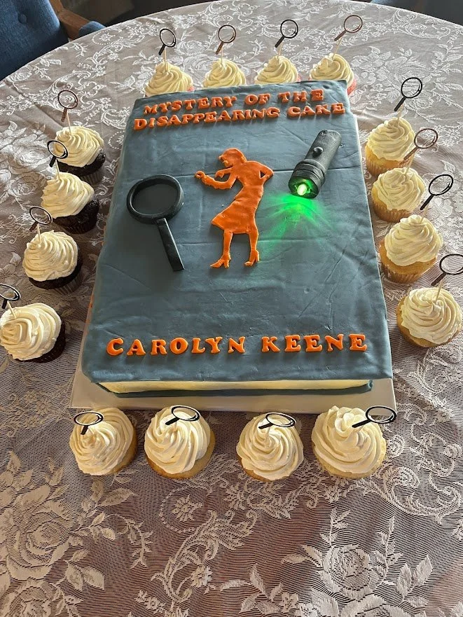 Nancy Drew Mystery Cake Book Replica in Buttercream Fondant Cutout Lettering Nancy Drew Figure Magnifying Glass and Flashlight with Real Illuminating Light Side Buttercream Frosted Cupcakes with Magnifying Glass Picks