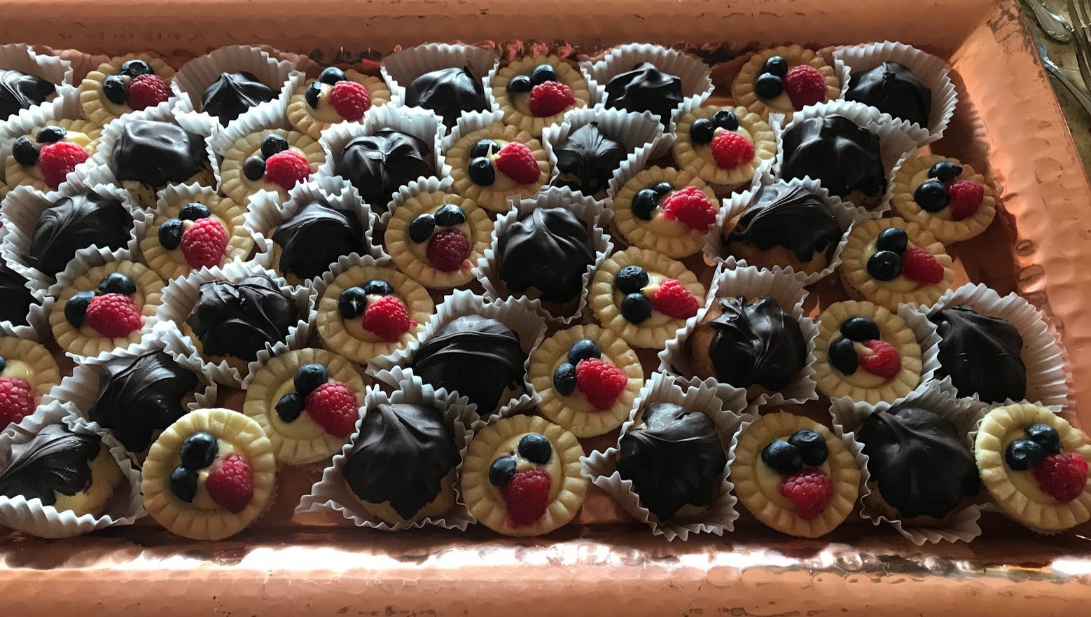 Dessert Assortment Fresh Berry Custard Tartlets and Chocolate Dipped Creampuffs On Copper  Platter