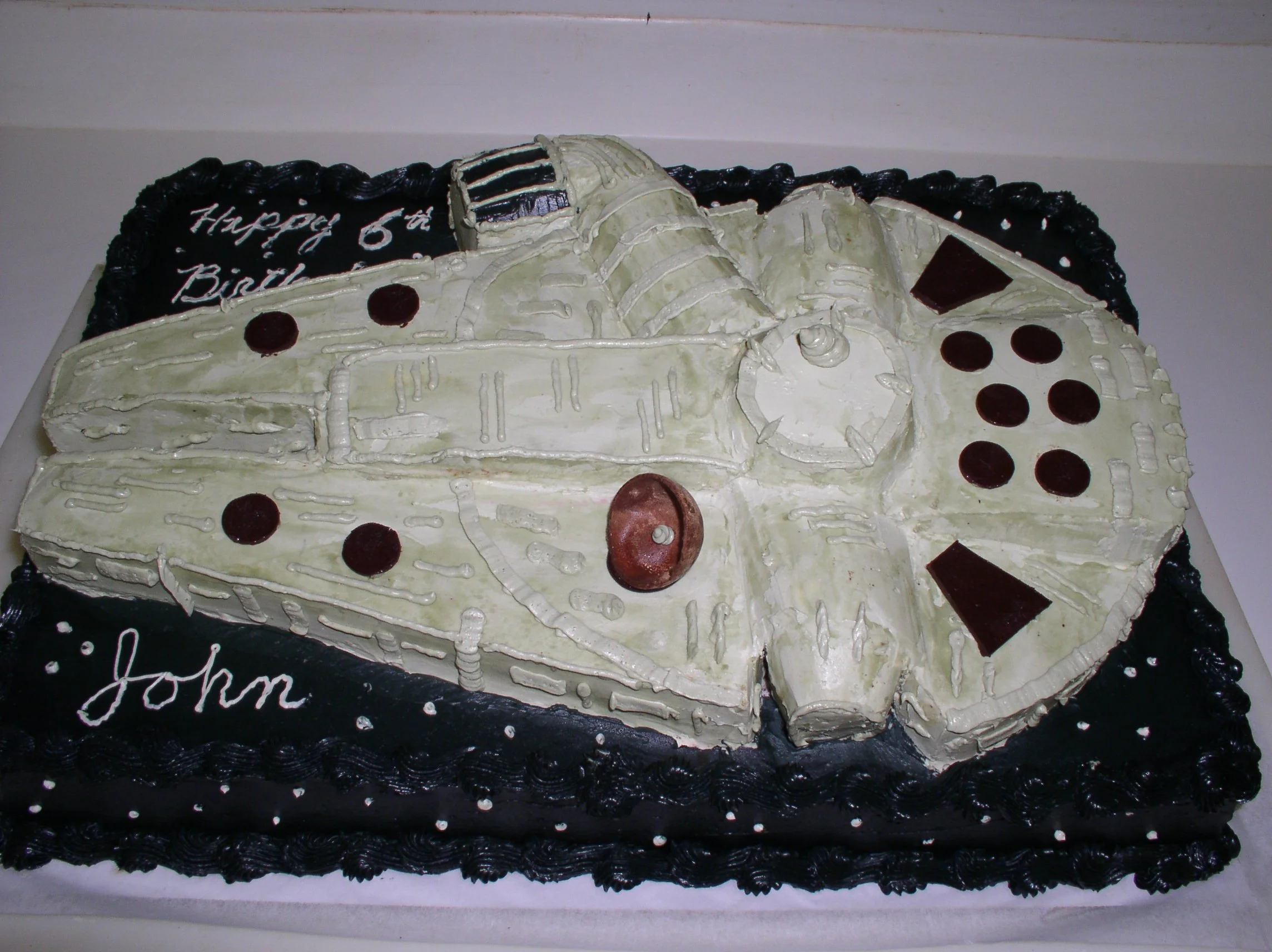 Stacked Sheet Cake Sculpted Star Wars Millennium Falcon over Black Buttercream Frosting with White Points of Life 