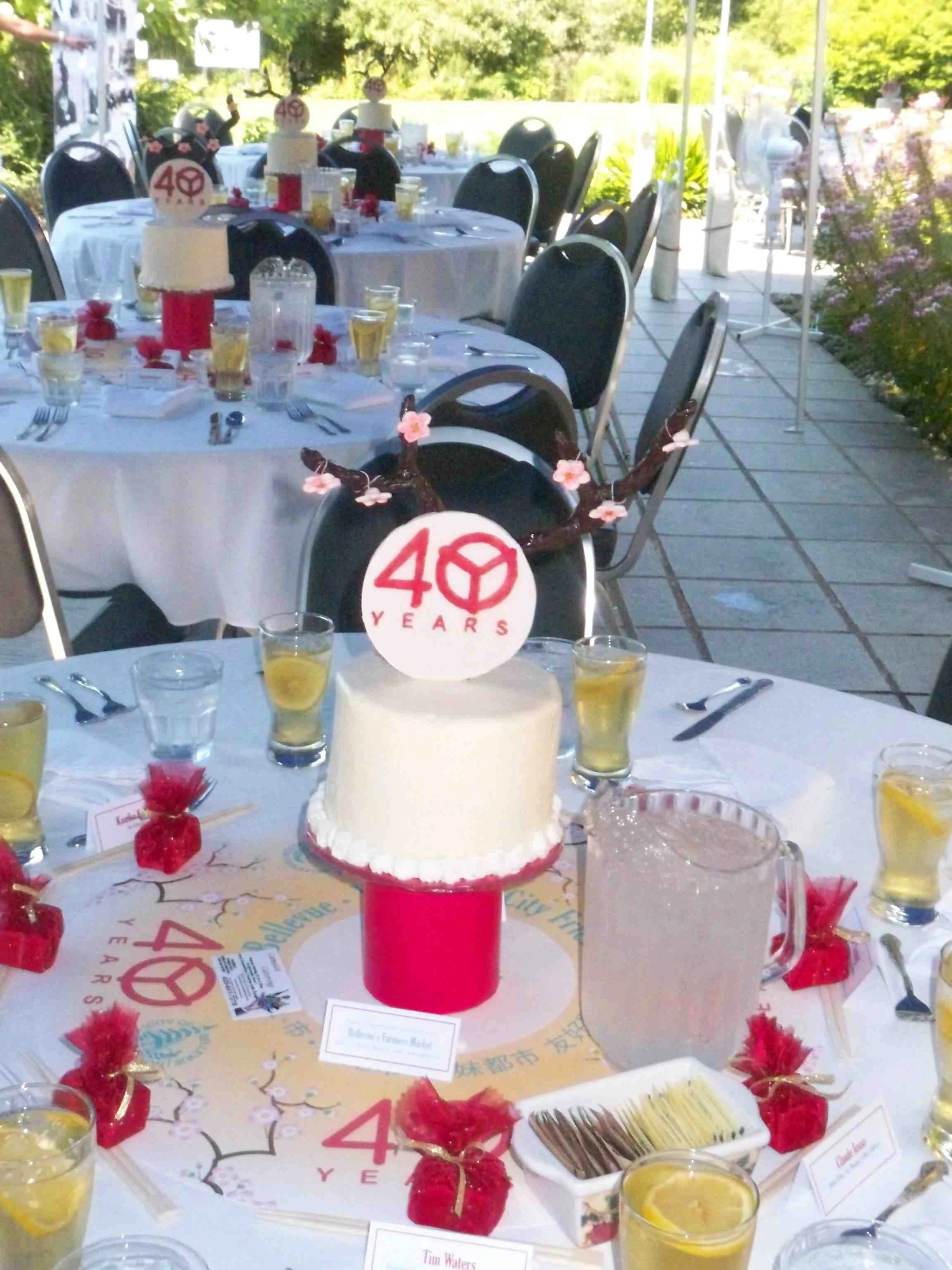 40 Year Commemorative Cake Celebrating City Bellevue Sisterhood Single Round Buttercream Frosted Six Inch Cake on Red Wrapped Pillar Sugar Porcelain Cake Top Emblem