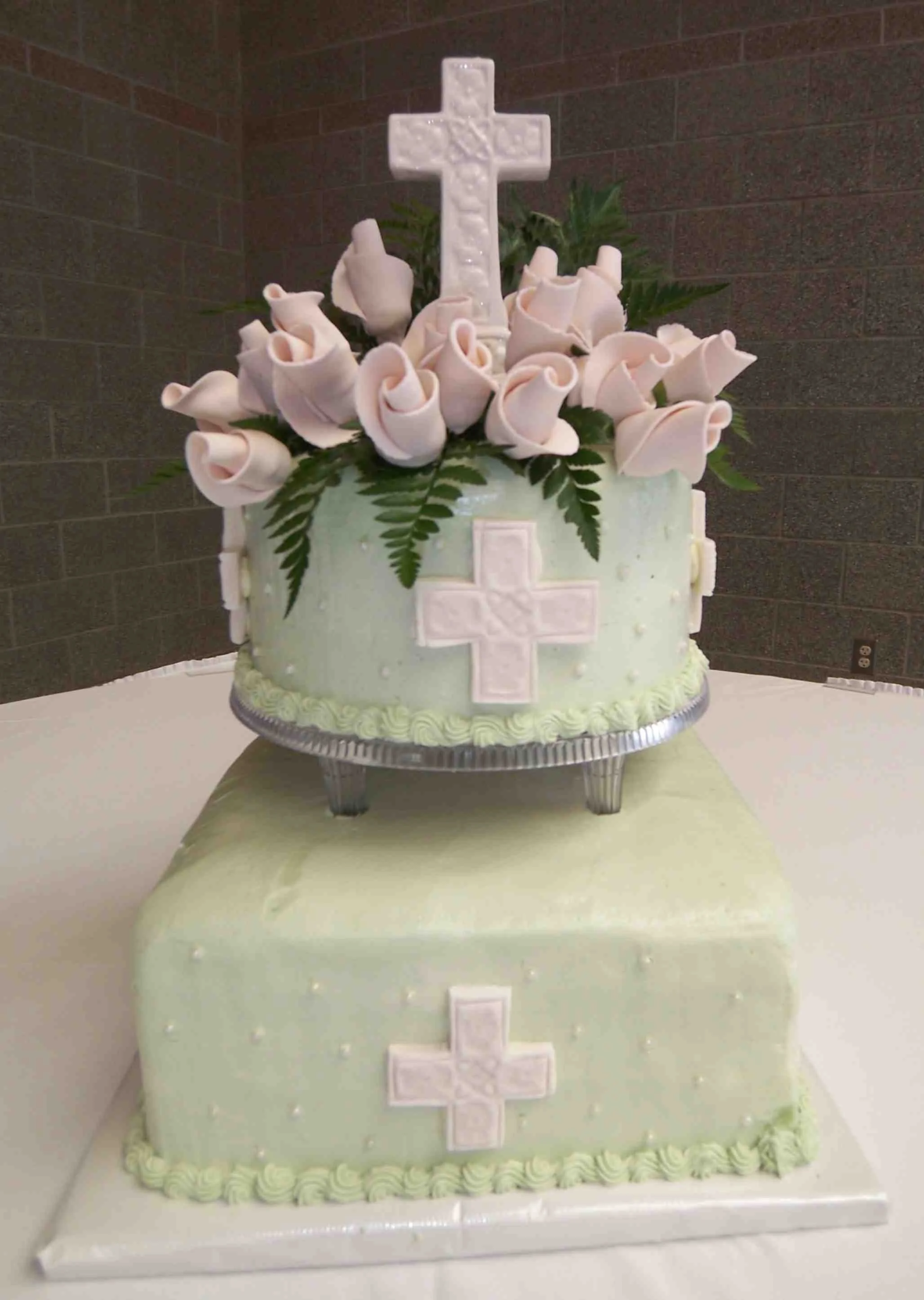 Celtic inspired two tier square and round separated wedding cake sage colored buttercream frosting three dimensional impressed fondant crosses white sugar porcelain but rose bouquet over fresh sword fern 