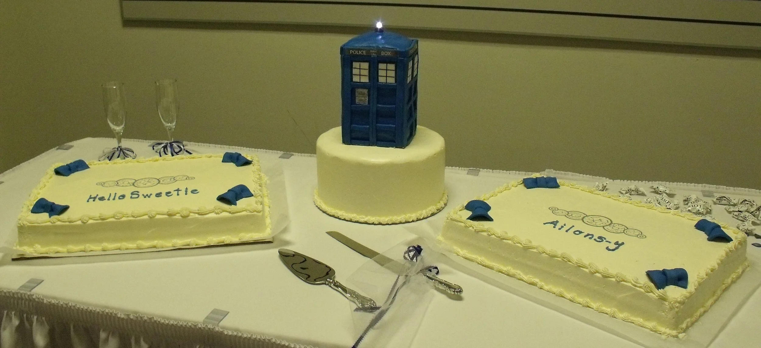 Dr Who Themed Wedding Two Half Sheet Cakes with Blue Fondant Bow Ties Rice Paper Decor Ten Inch Round Torte Split Cake Eight Inch Tall Sculpted Fondant Cake Tardis with Beacon Light All Cakes Are Buttercream Frosted