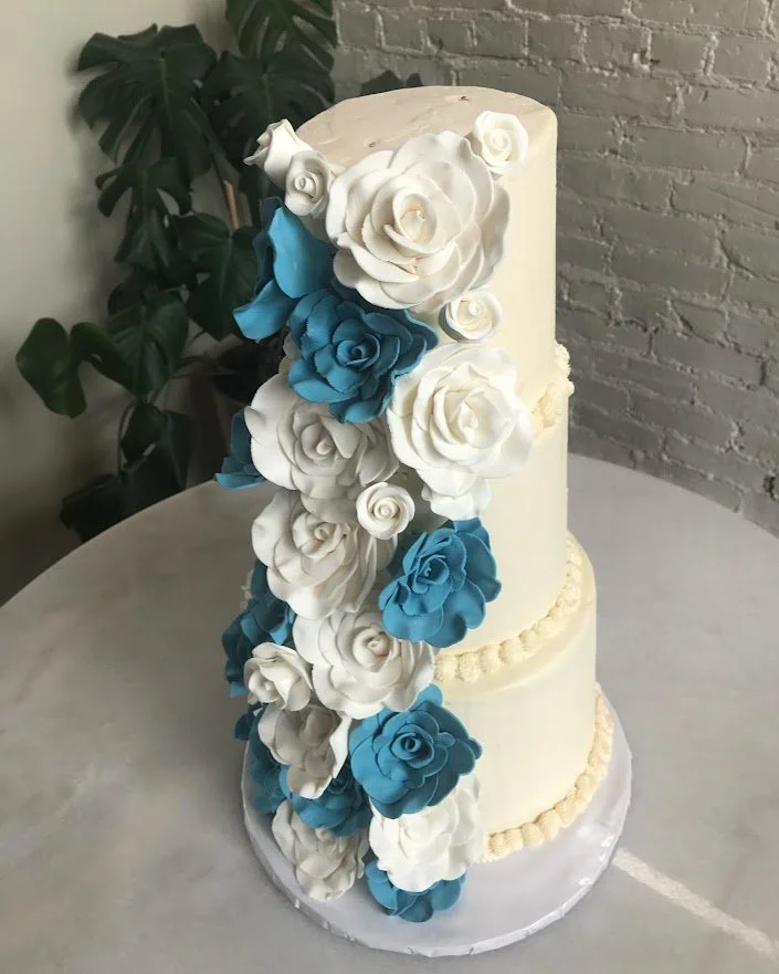 Three tier buttercream frosted tower wedding cake Sugar White and Dusty blue Hibiscus flowers white rosebuds